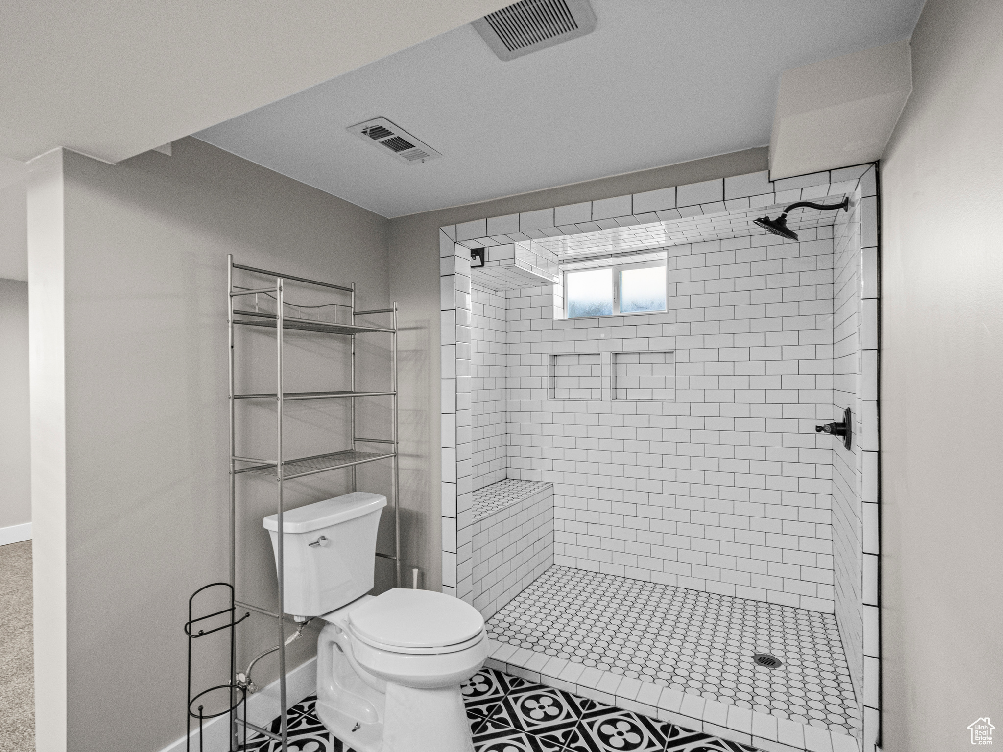 Bathroom with tile patterned floors, toilet, and tiled shower