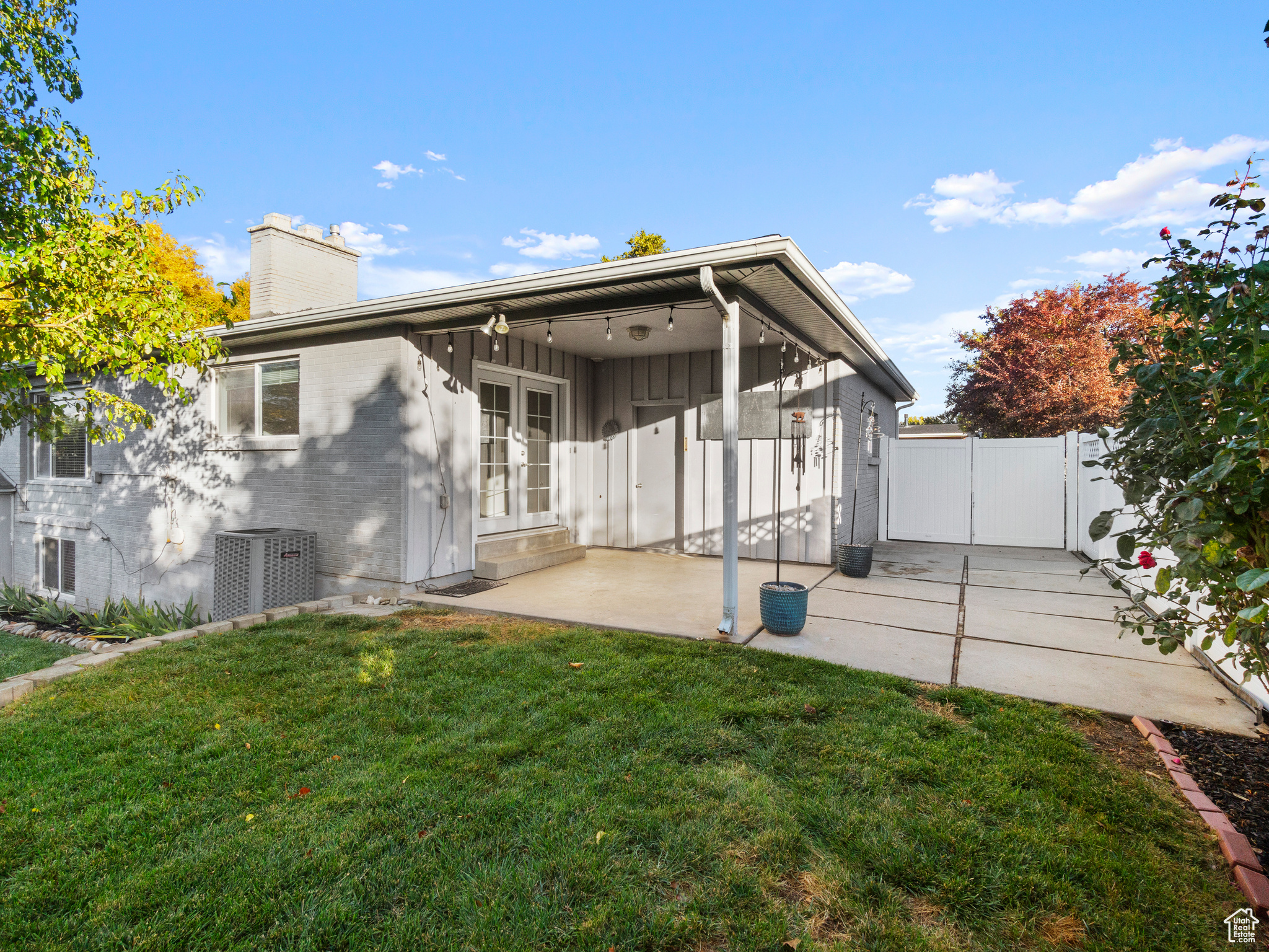 Back of house featuring cooling unit, a patio area, and a lawn