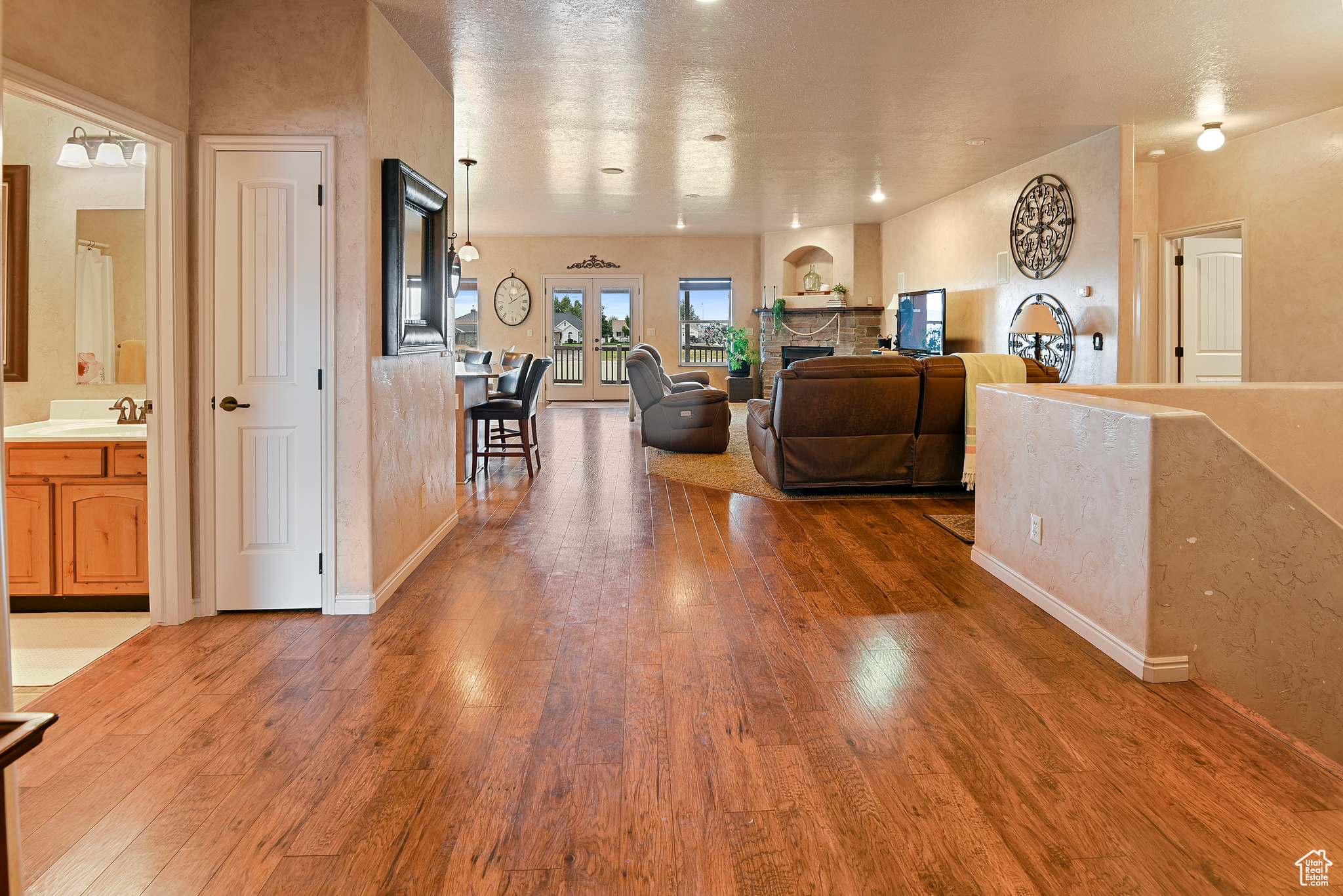 Living room with wood-type flooring, a stone fireplace, and sink