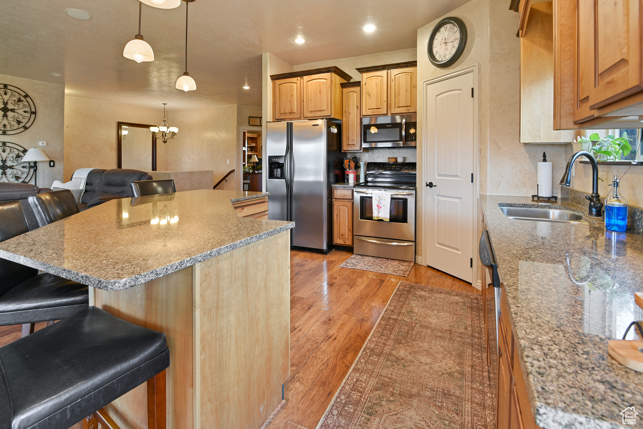 Kitchen with a kitchen bar, appliances with stainless steel finishes, light hardwood / wood-style floors, and sink