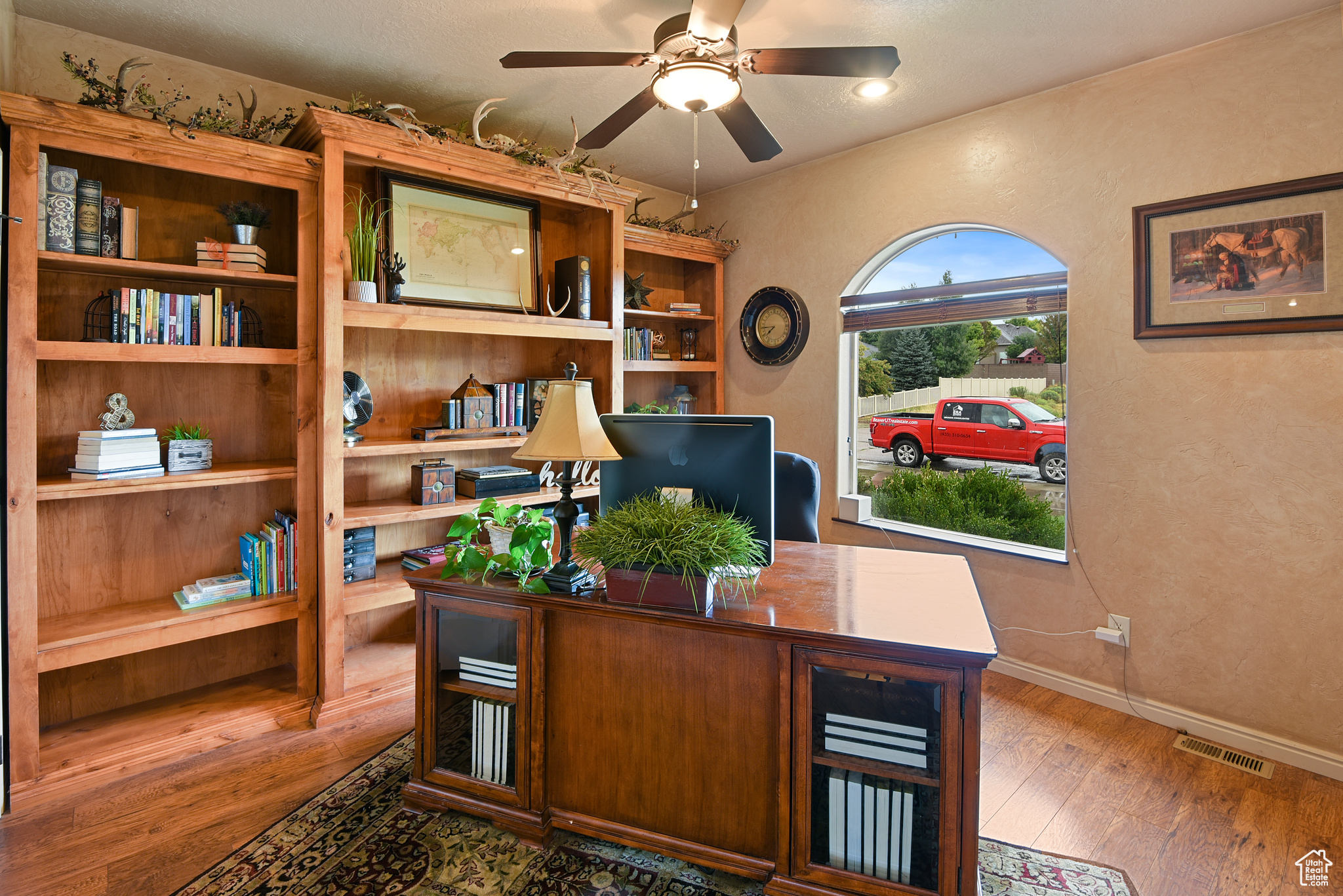 Office area with ceiling fan and dark wood-type flooring