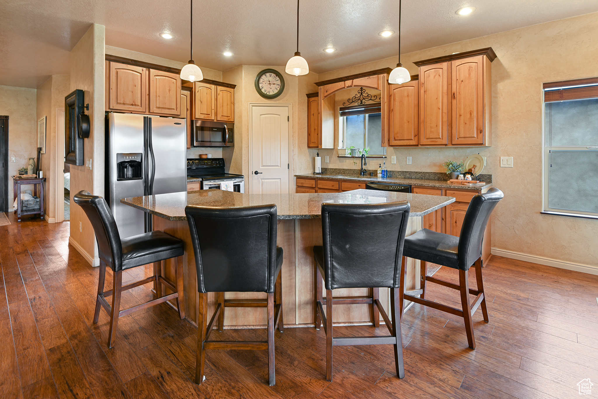 Kitchen featuring dark stone countertops, dark hardwood / wood-style flooring, a kitchen island, and appliances with stainless steel finishes