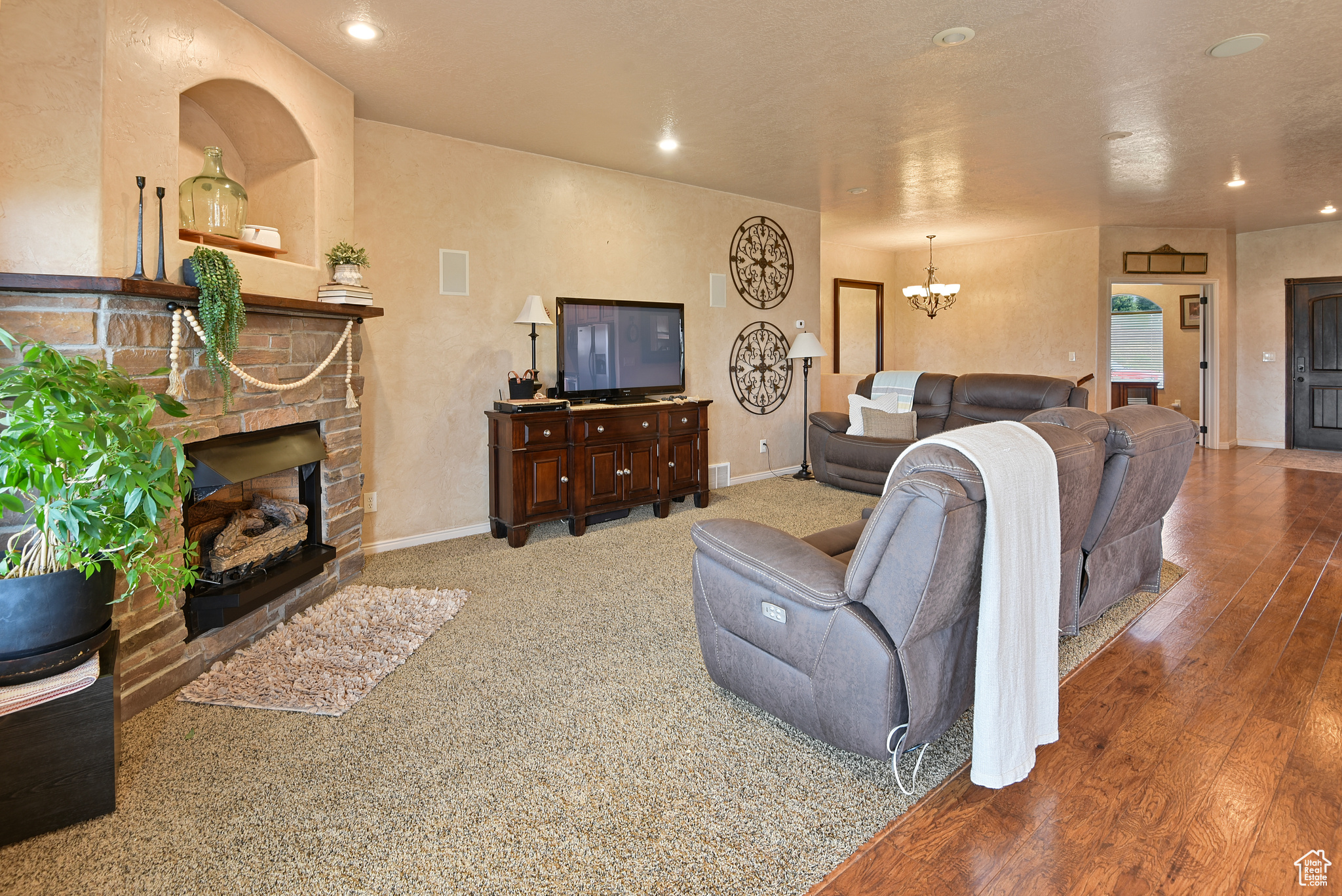 Living room with a brick fireplace, a notable chandelier, and hardwood / wood-style flooring