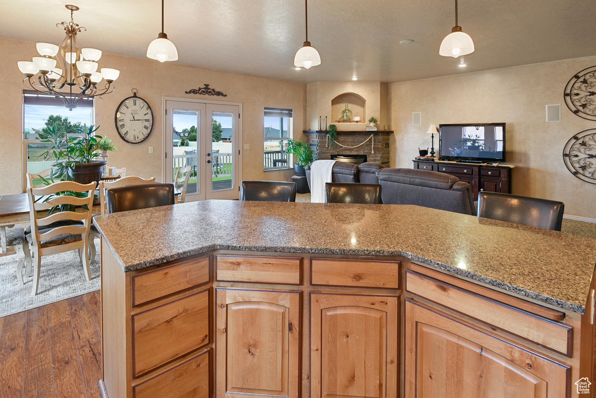 Kitchen with french doors, a stone fireplace, dark hardwood / wood-style floors, a notable chandelier, and pendant lighting