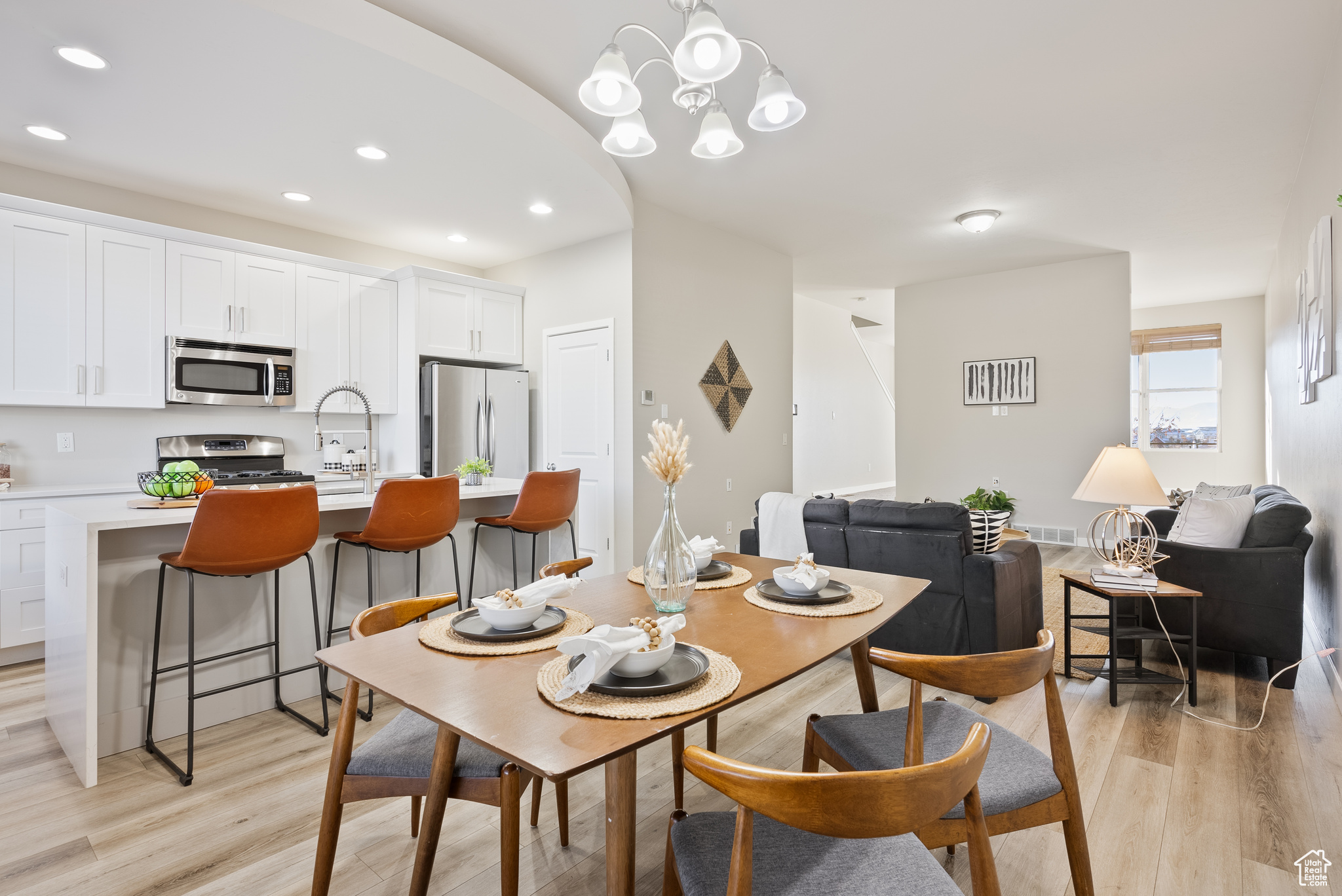 Dining area with sink, an inviting chandelier, and light wood-type flooring