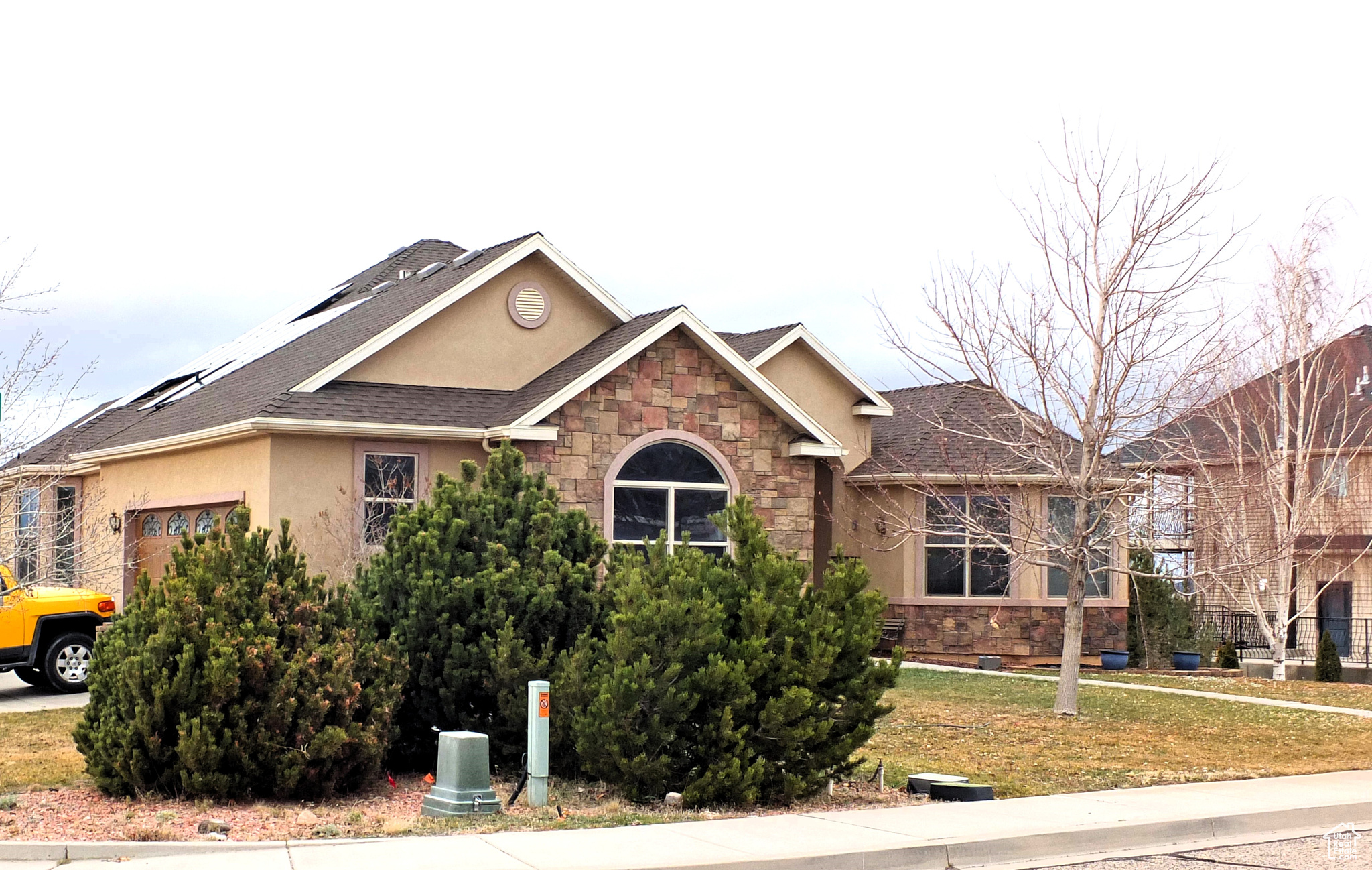 View of front facade featuring solar panels, a garage, and a front lawn