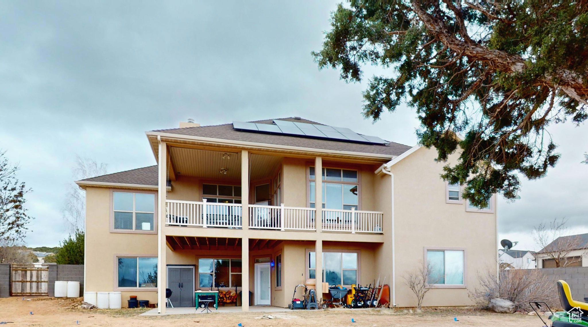 Back of property featuring solar panels, a balcony, and a patio