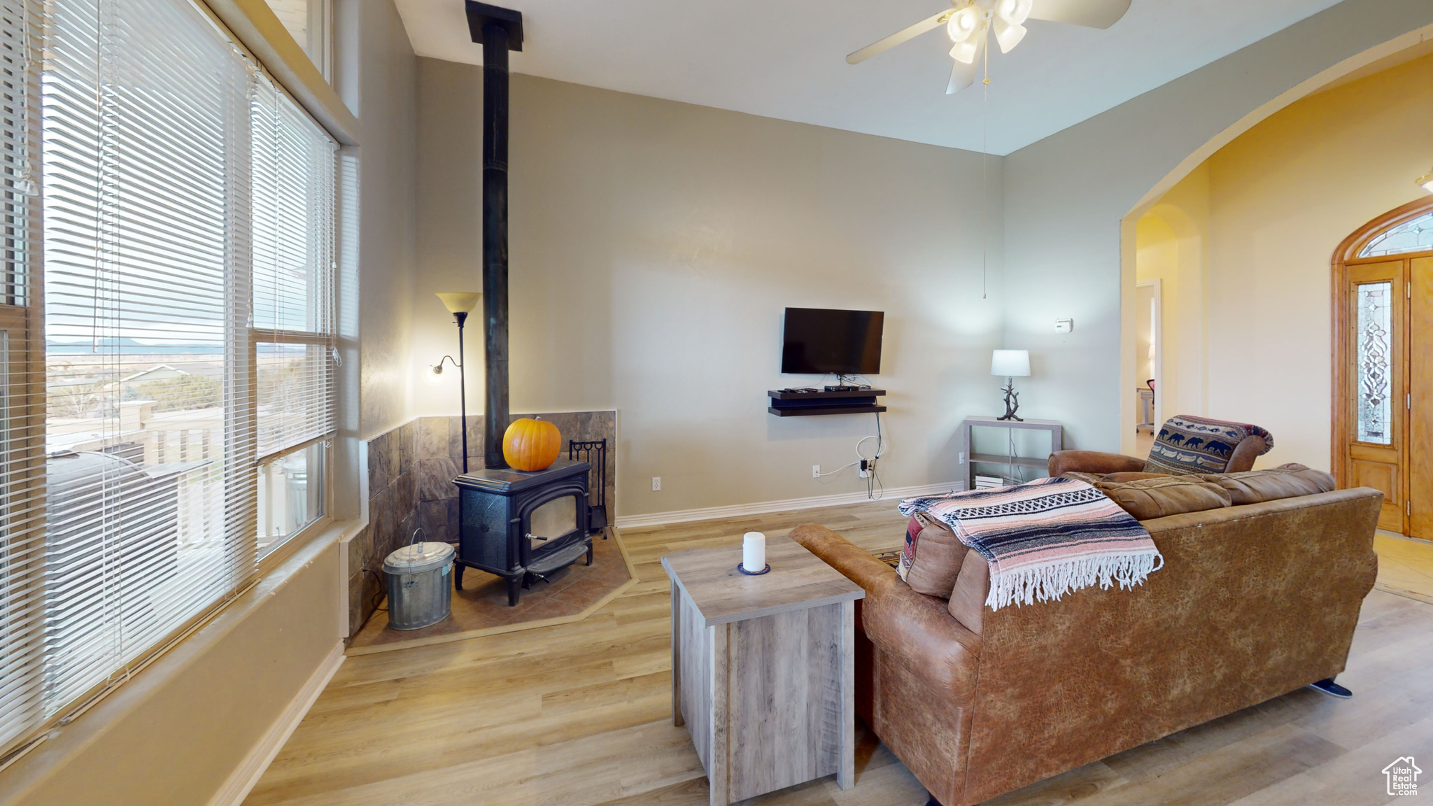 Living room featuring light hardwood / wood-style floors, a wood stove, and ceiling fan