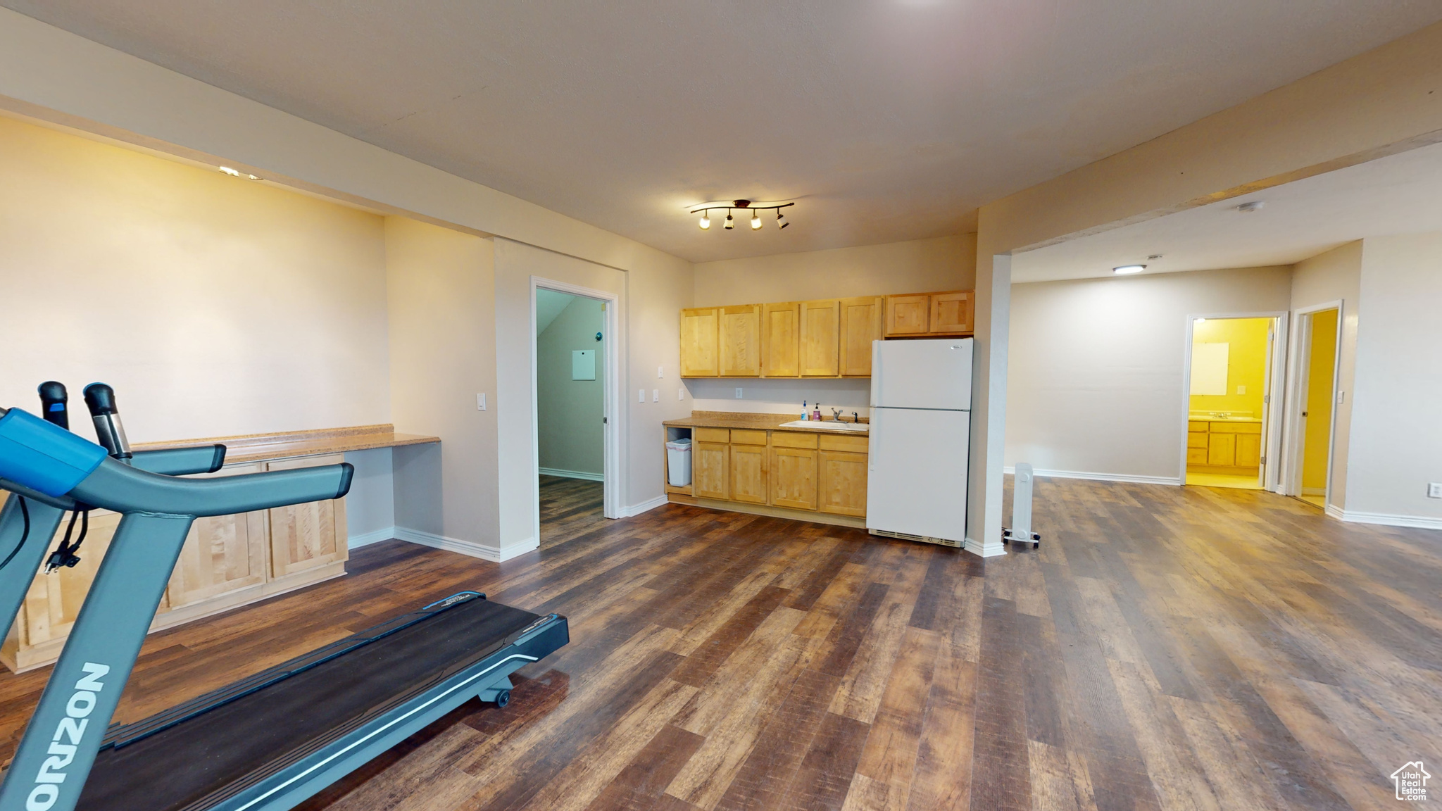 Kitchen with white refrigerator, sink, dark wood-type flooring, and light brown cabinetry