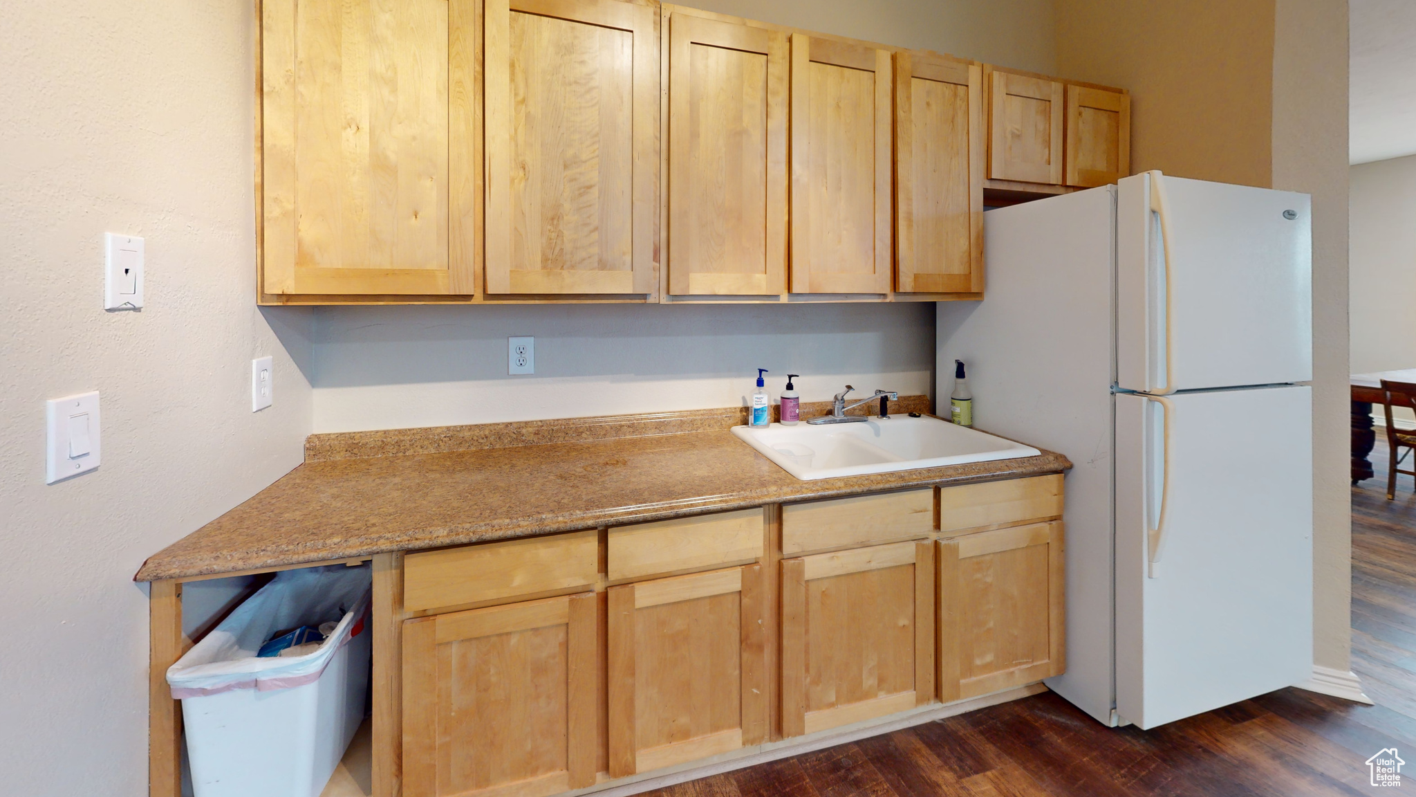 Kitchen featuring light brown cabinets, white refrigerator, dark wood-type flooring, and sink