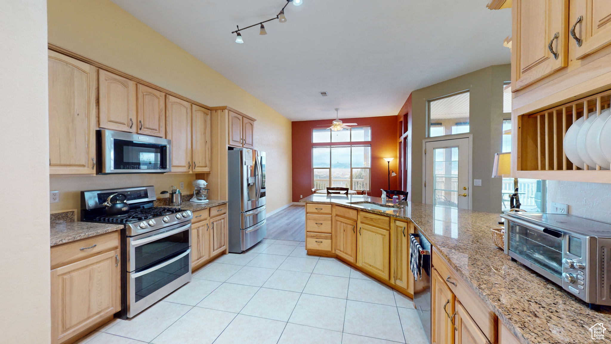 Kitchen with kitchen peninsula, light brown cabinets, stainless steel appliances, and ceiling fan