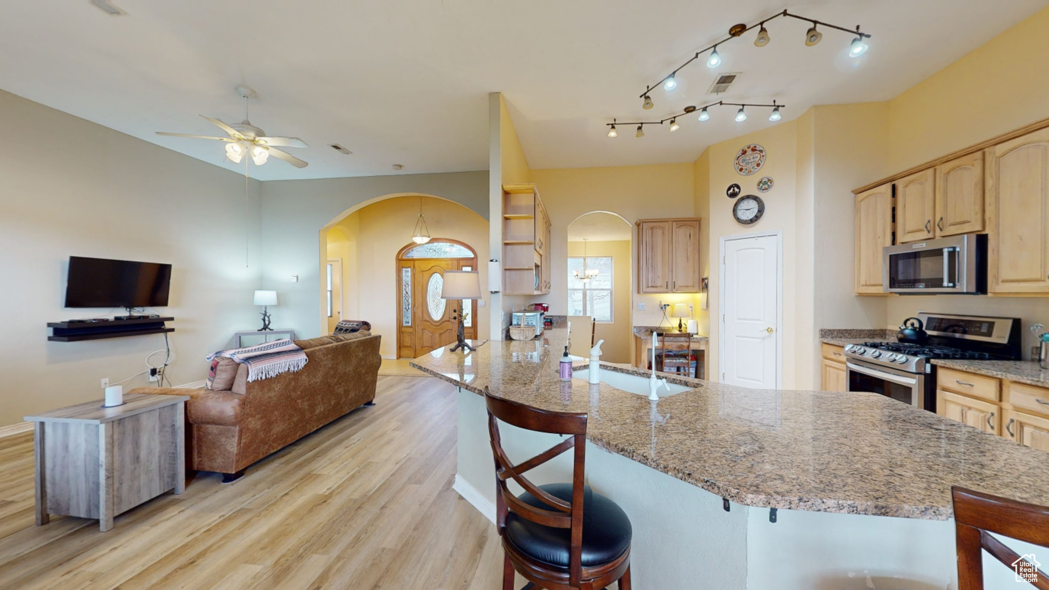 Kitchen with a kitchen bar, appliances with stainless steel finishes, light wood-type flooring, kitchen peninsula, and sink