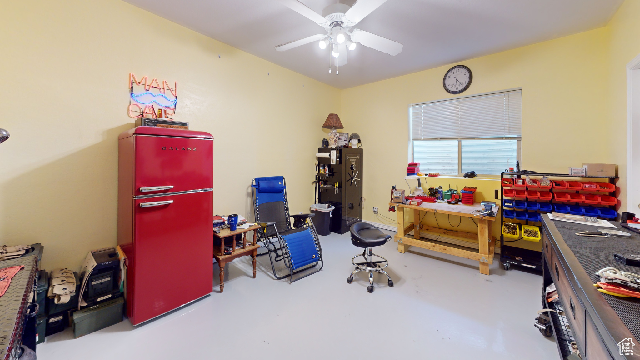 Playroom with a workshop area, ceiling fan, and concrete floors