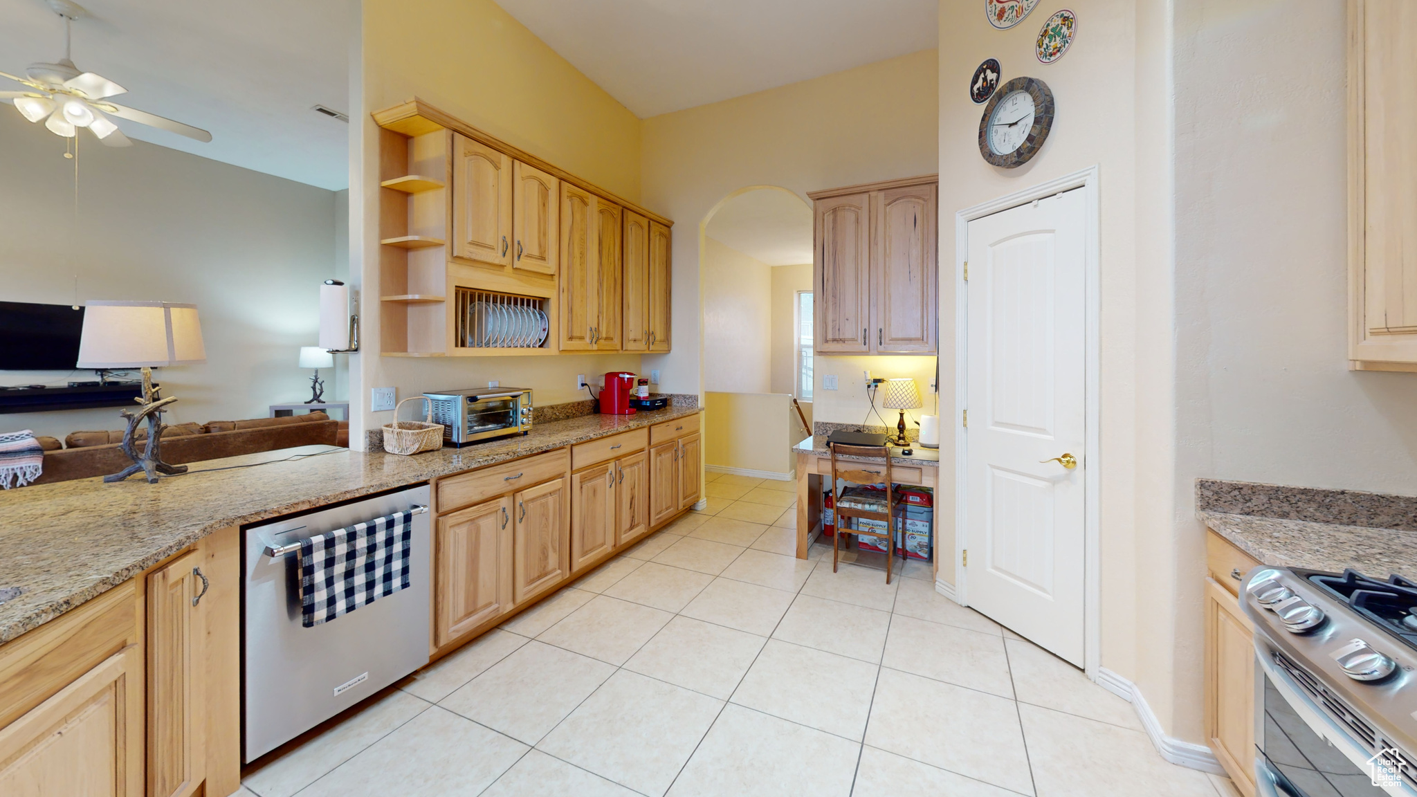 Kitchen featuring appliances with stainless steel finishes, light stone counters, ceiling fan, light brown cabinets, and light tile patterned floors