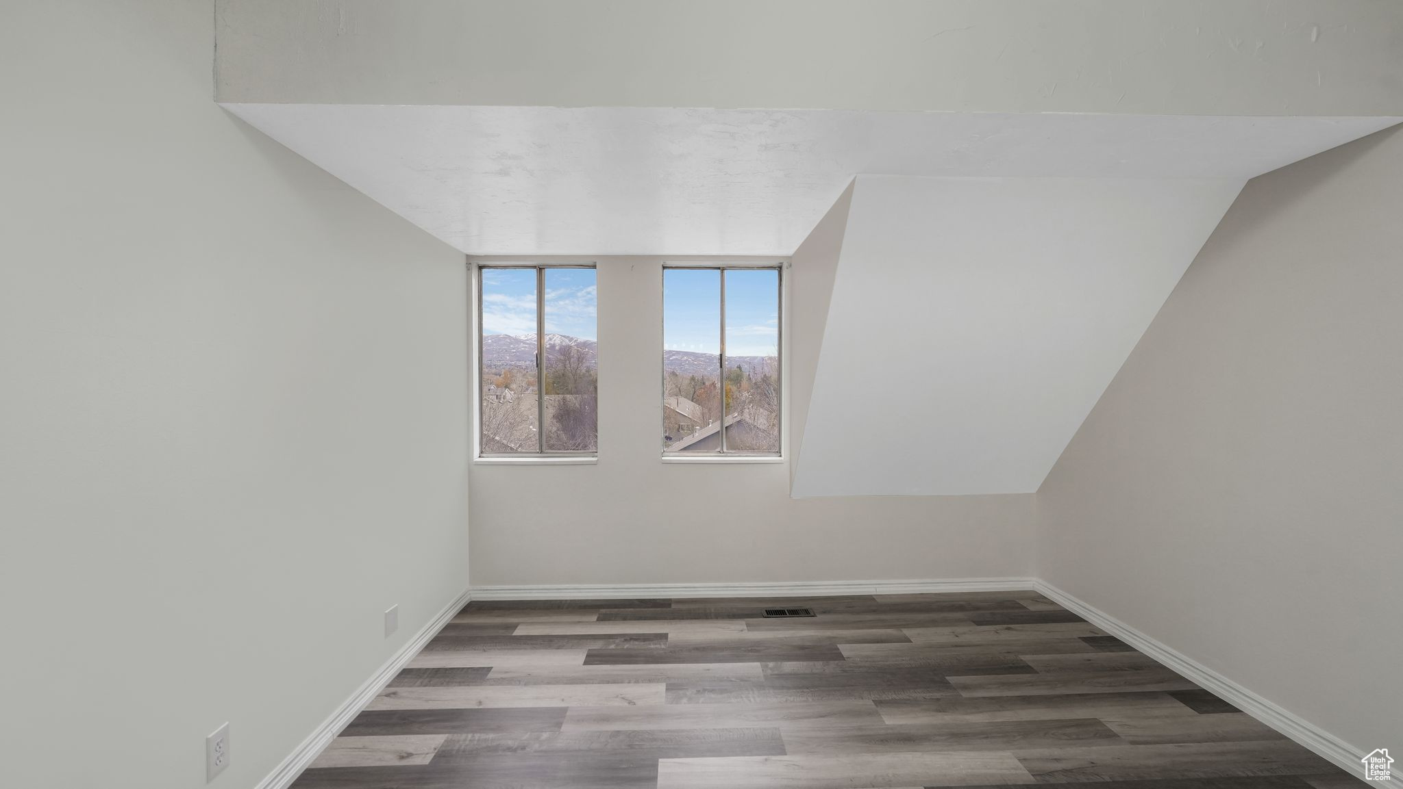 Unfurnished room with hardwood / wood-style floors and lofted ceiling