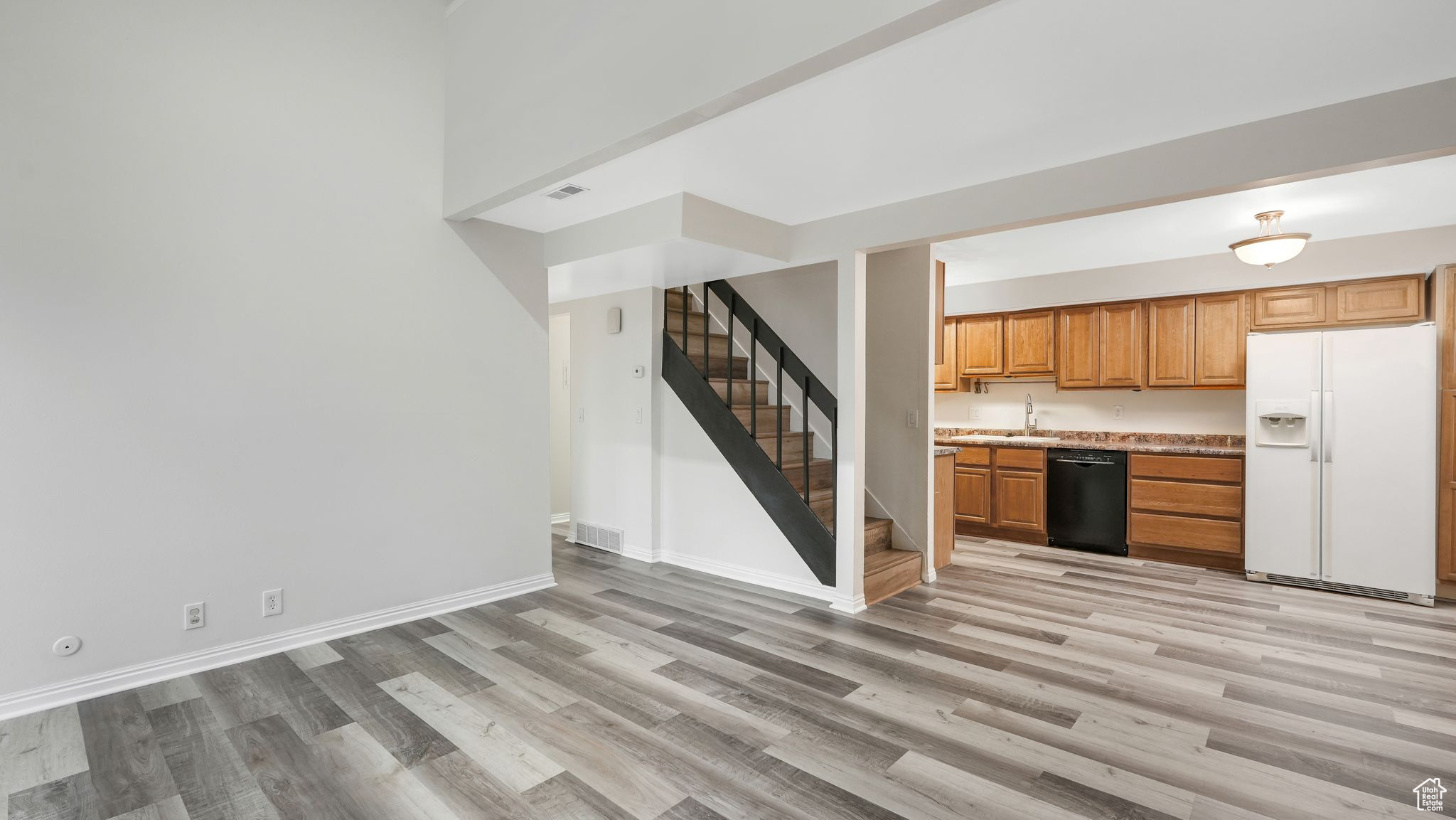 Kitchen with dishwasher, light hardwood / wood-style floors, white refrigerator with ice dispenser, and sink