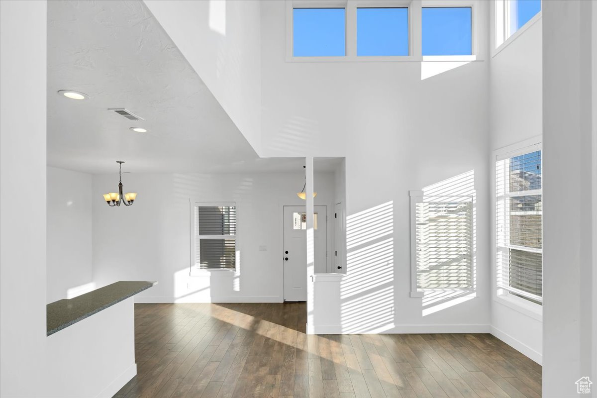 Interior space featuring a high ceiling, dark hardwood / wood-style floors, a wealth of natural light, and a notable chandelier