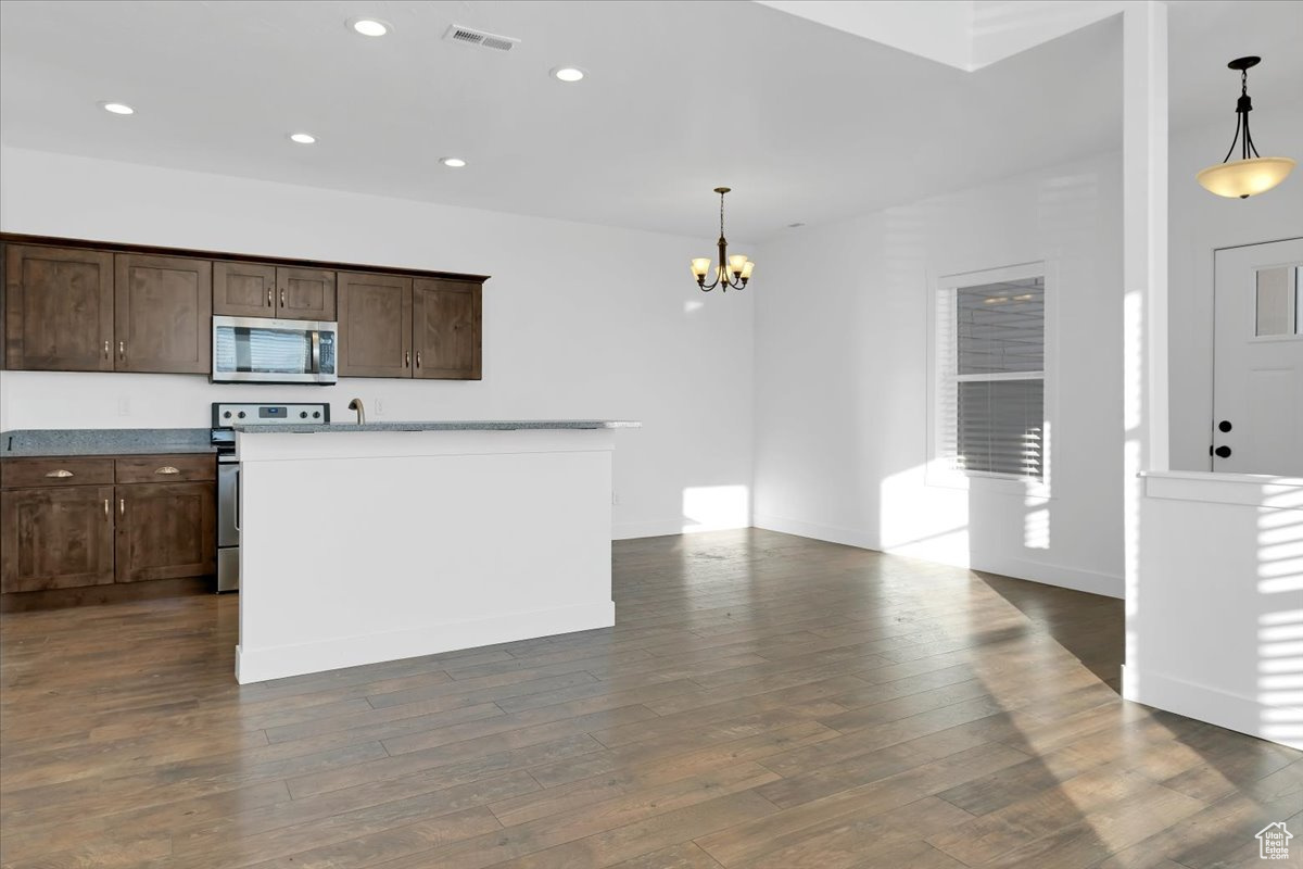 Kitchen with dark brown cabinetry, stainless steel appliances, dark hardwood / wood-style floors, a chandelier, and decorative light fixtures