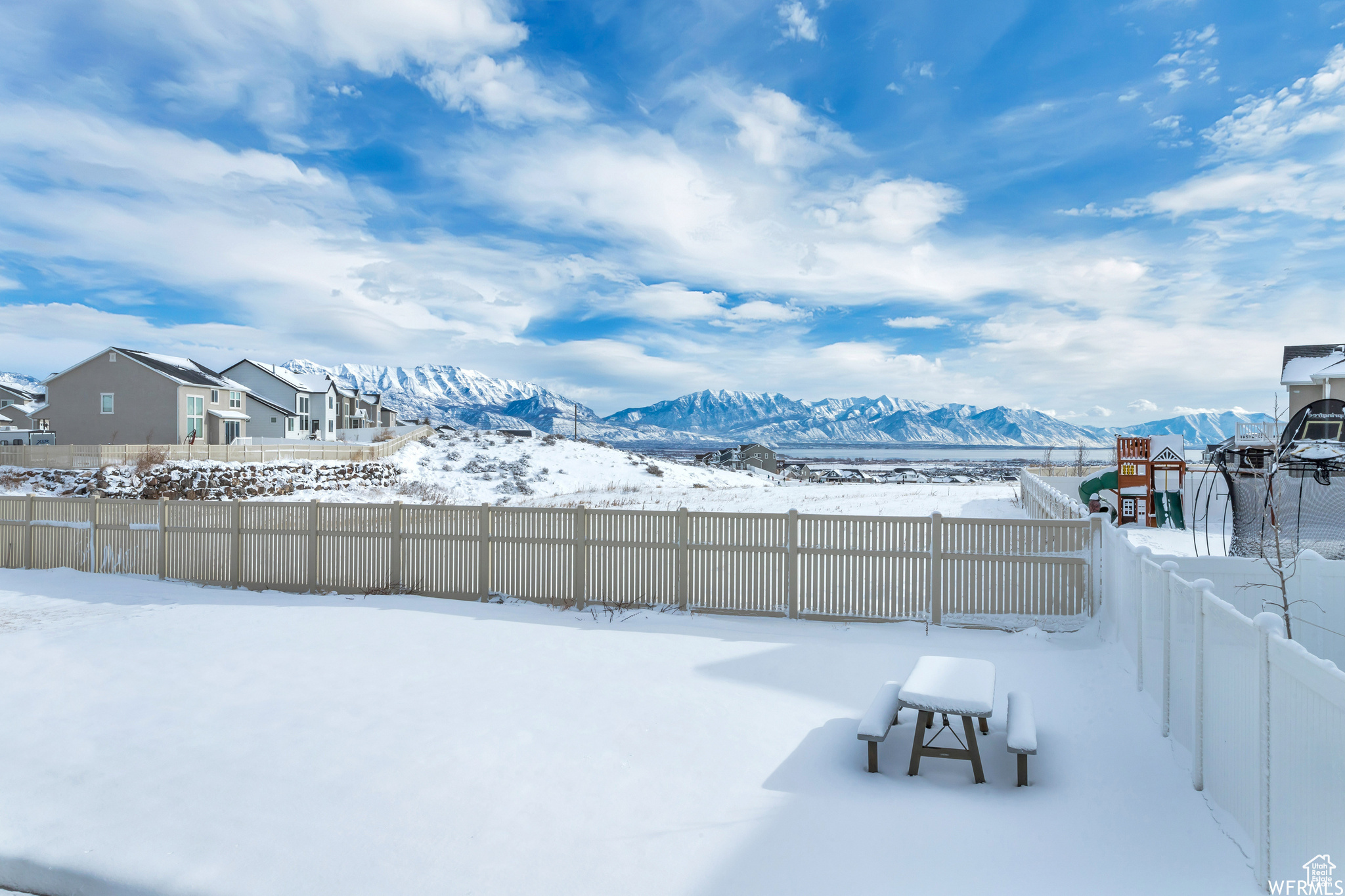 Yard layered in snow featuring a mountain view and a playground