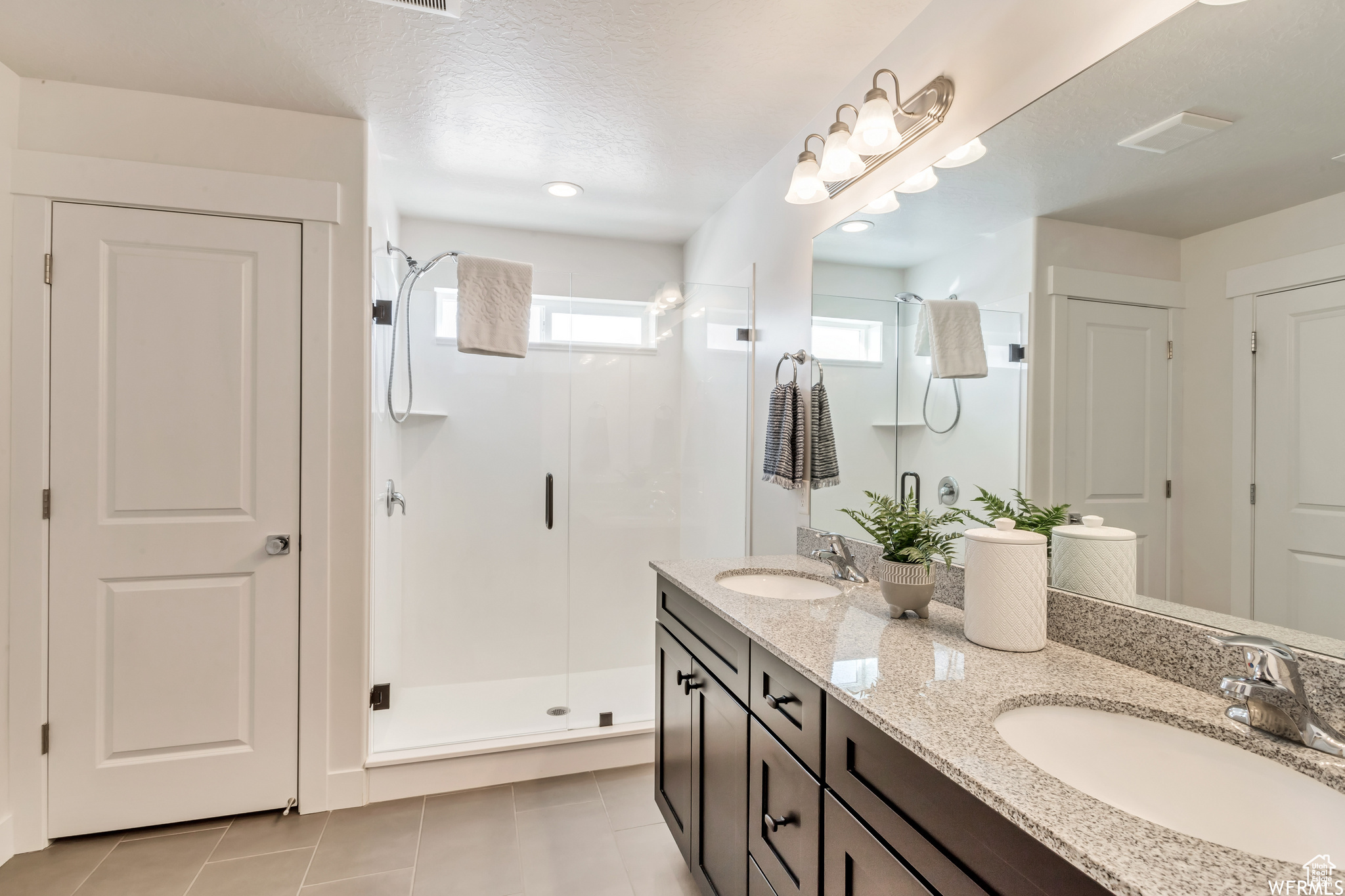 Bathroom with tile patterned flooring, vanity, a textured ceiling, and walk in shower