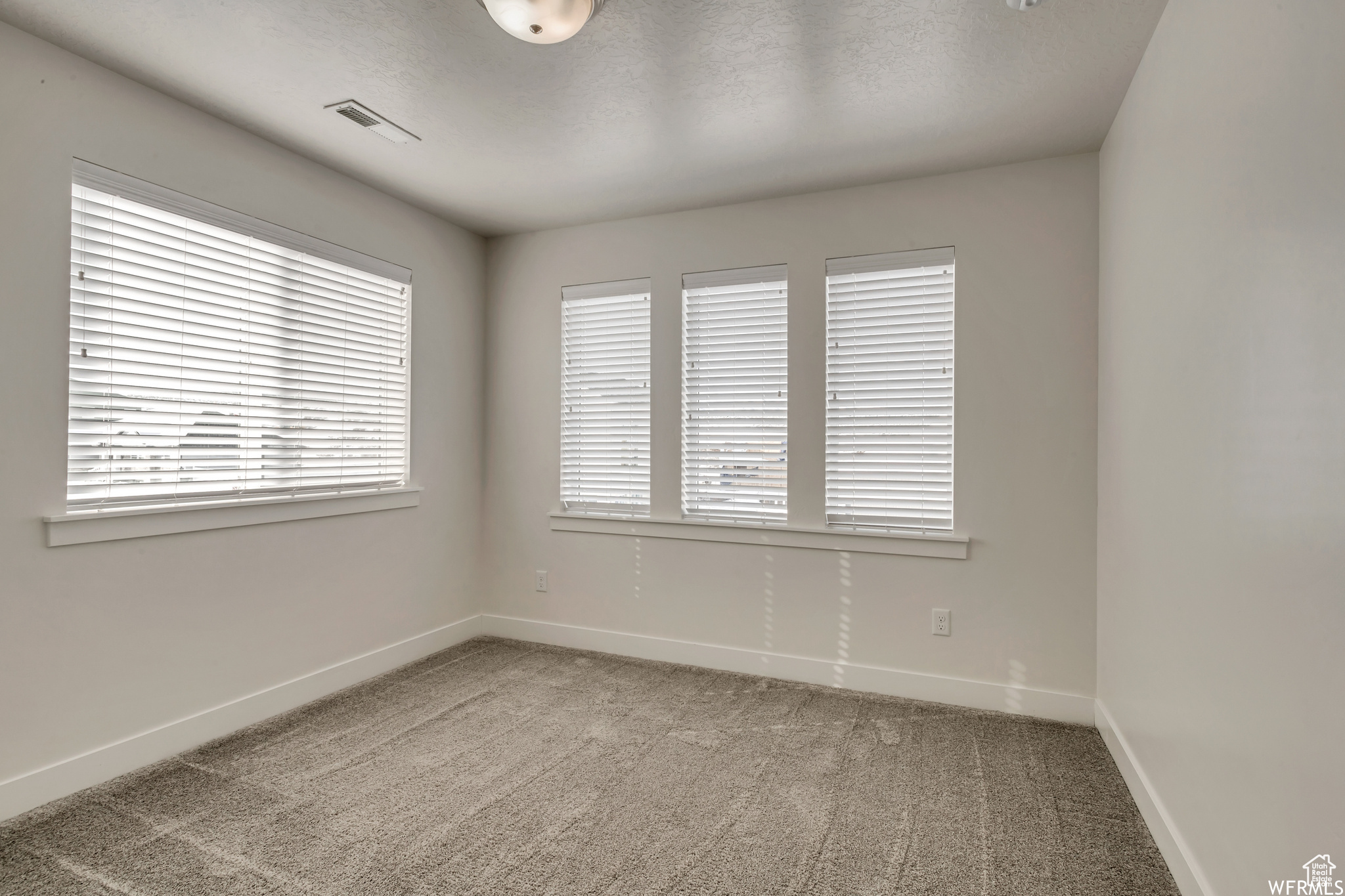 Carpeted spare room featuring a textured ceiling