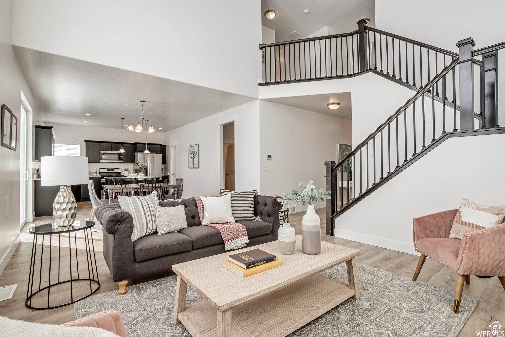 Living room with light hardwood / wood-style floors, a high ceiling, and a chandelier