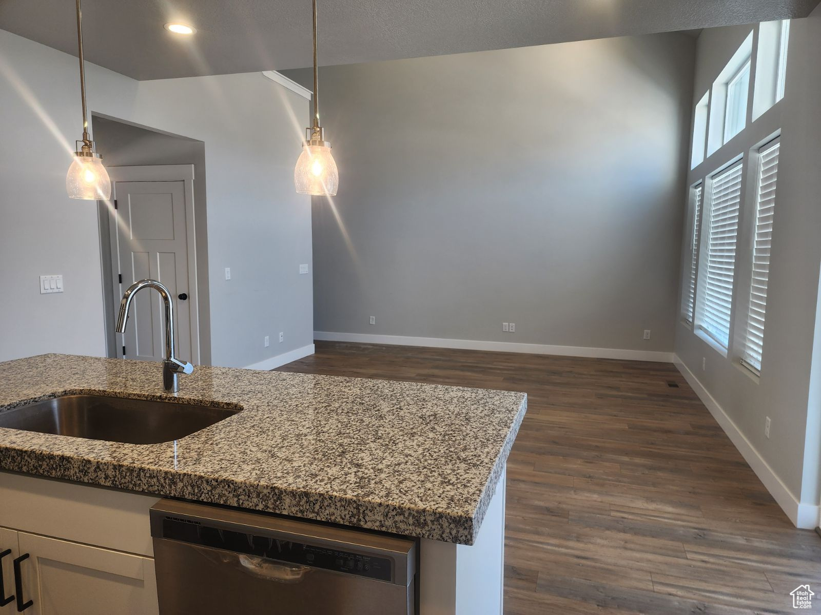 Kitchen with dishwasher, pendant lighting, stone countertops, and sink