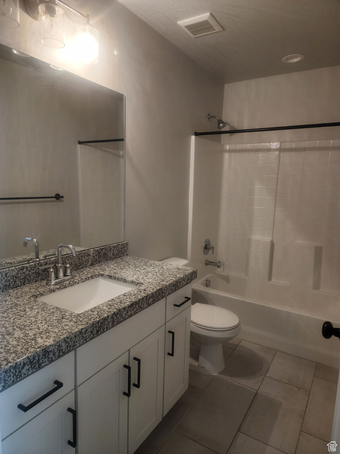 Full bathroom with tile patterned floors, vanity, bathtub / shower combination, and toilet