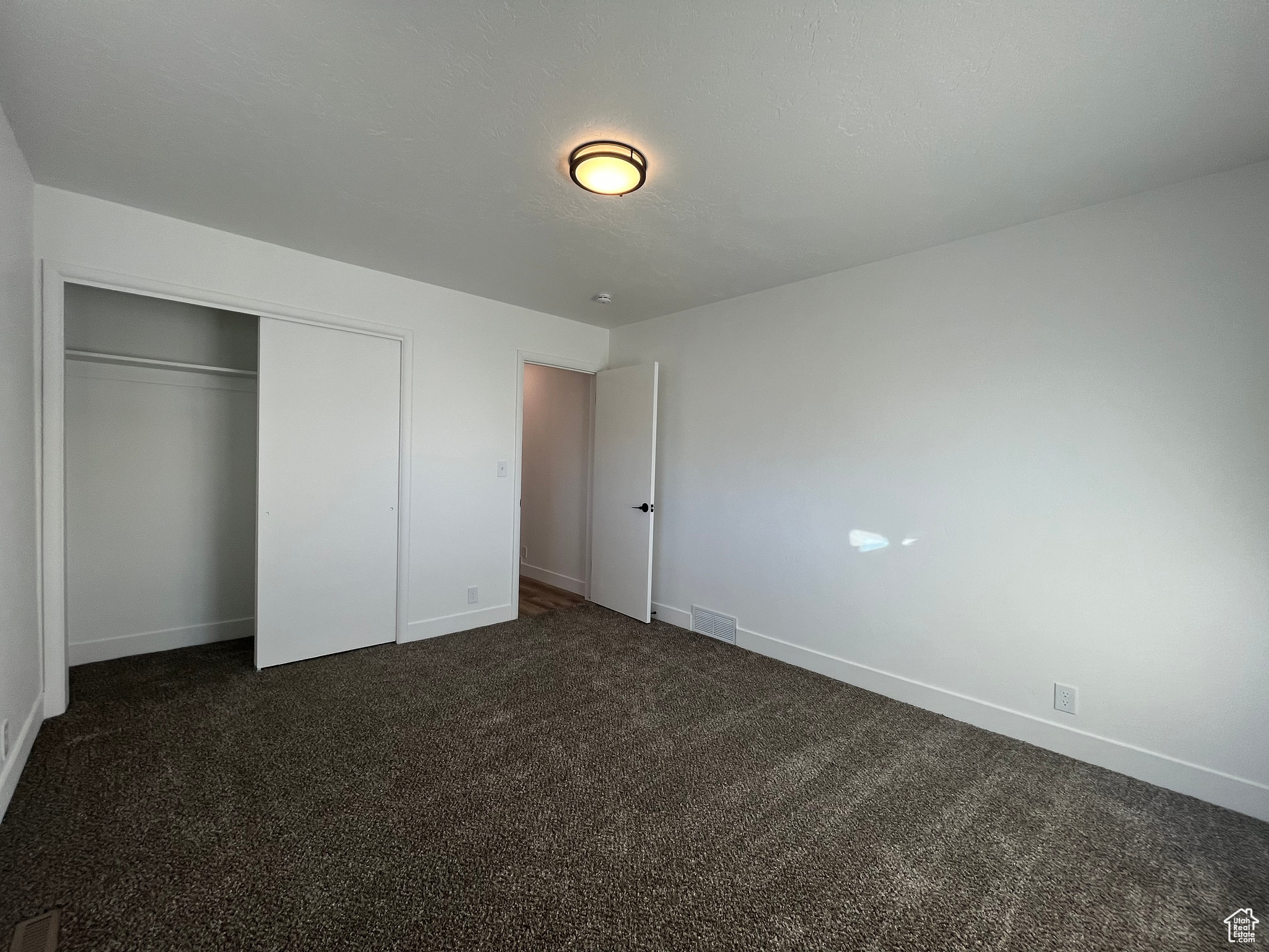 Unfurnished bedroom featuring a closet and dark carpet