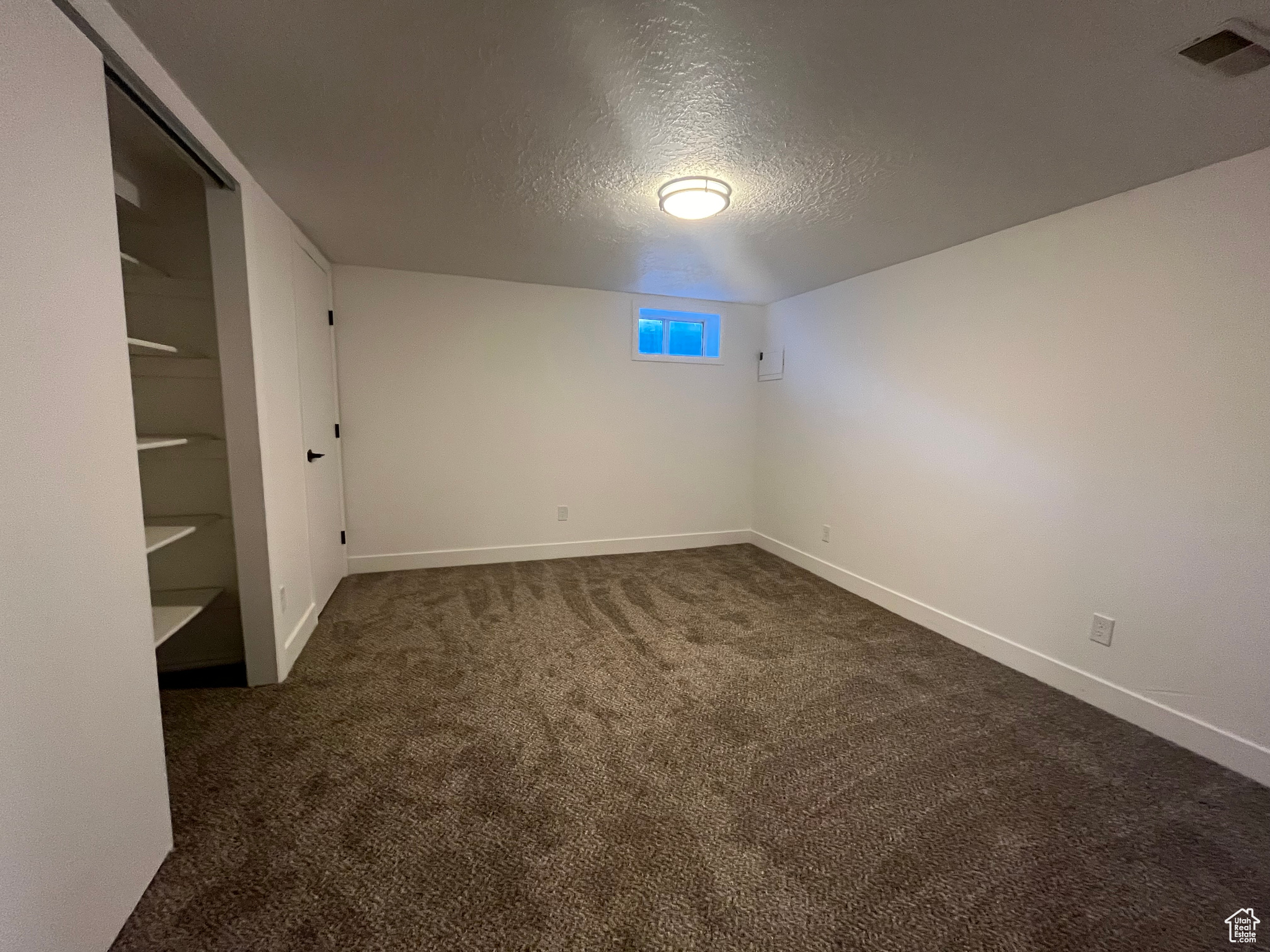 Carpeted spare room with a textured ceiling