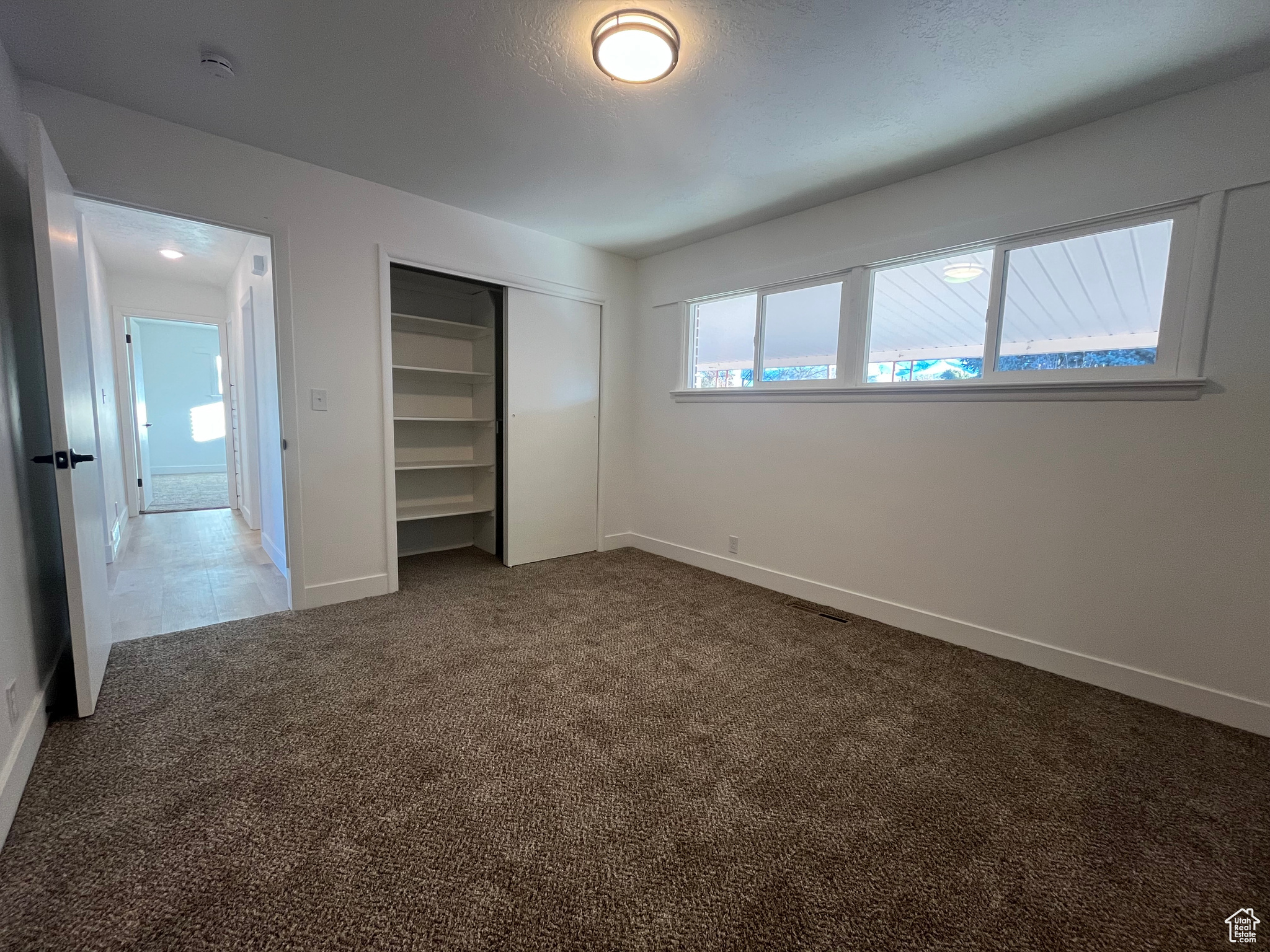 Unfurnished bedroom featuring carpet, a textured ceiling, and a closet