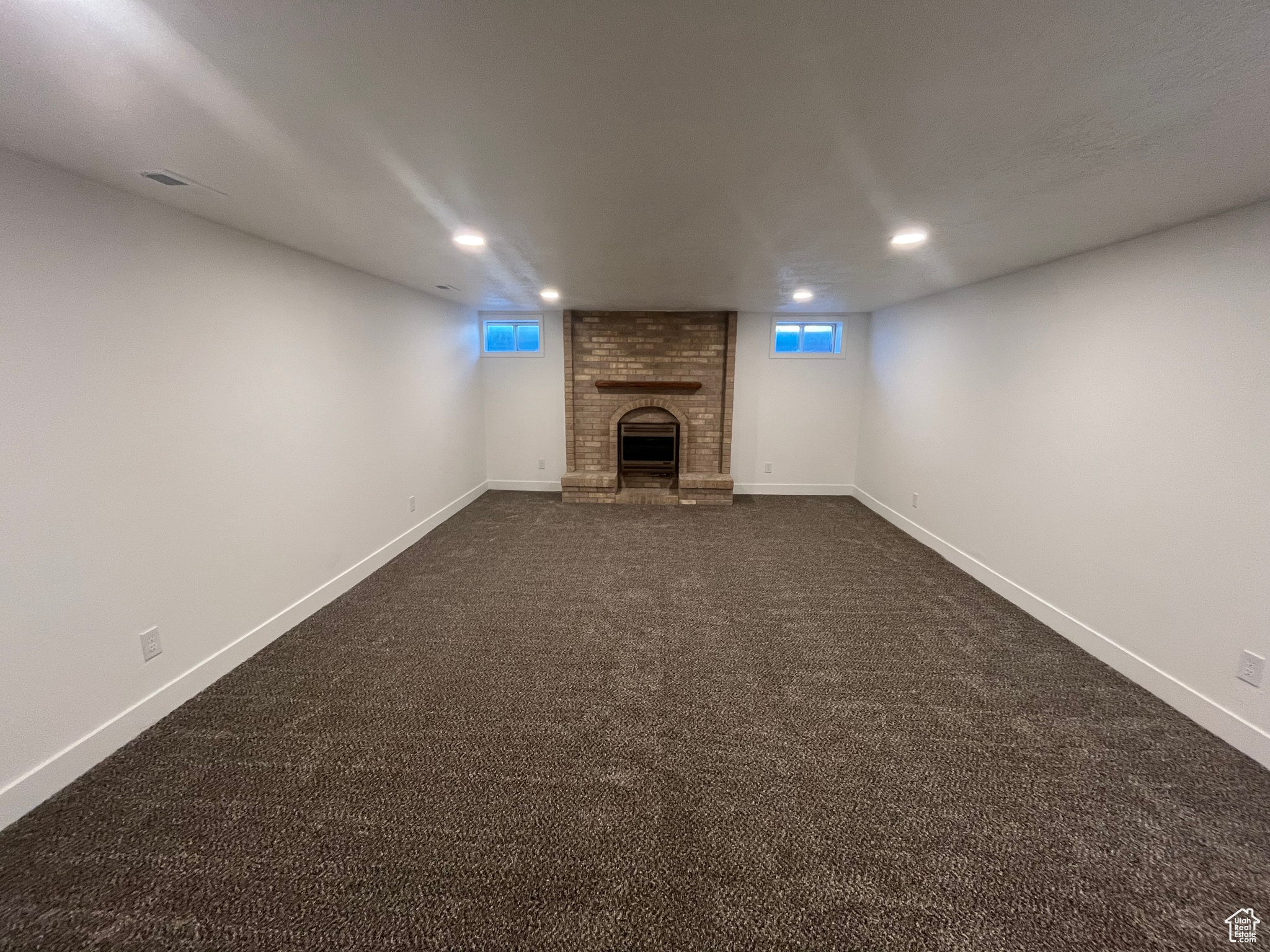 Basement featuring a fireplace, plenty of natural light, and dark colored carpet