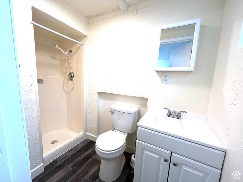 Bathroom featuring hardwood / wood-style floors, vanity, toilet, and walk in shower