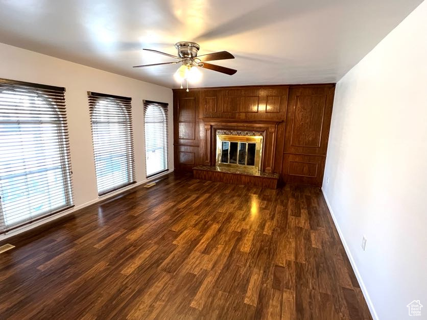 Unfurnished living room featuring ceiling fan, dark wood-type flooring, and a brick fireplace