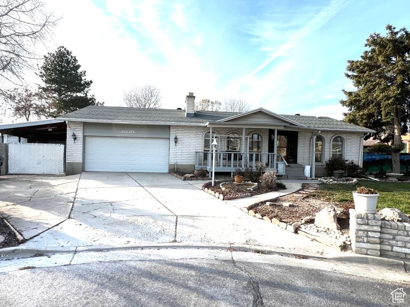 Ranch-style home featuring covered porch, a garage, and a carport