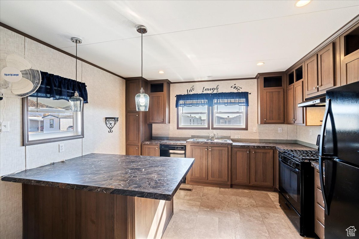 Kitchen with hanging light fixtures, ornamental molding, sink, and black appliances