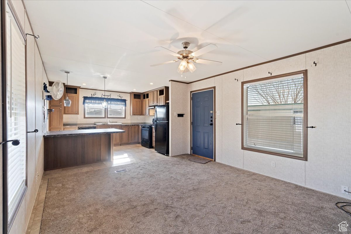 Kitchen with ceiling fan, black appliances, light carpet, decorative light fixtures, and kitchen peninsula