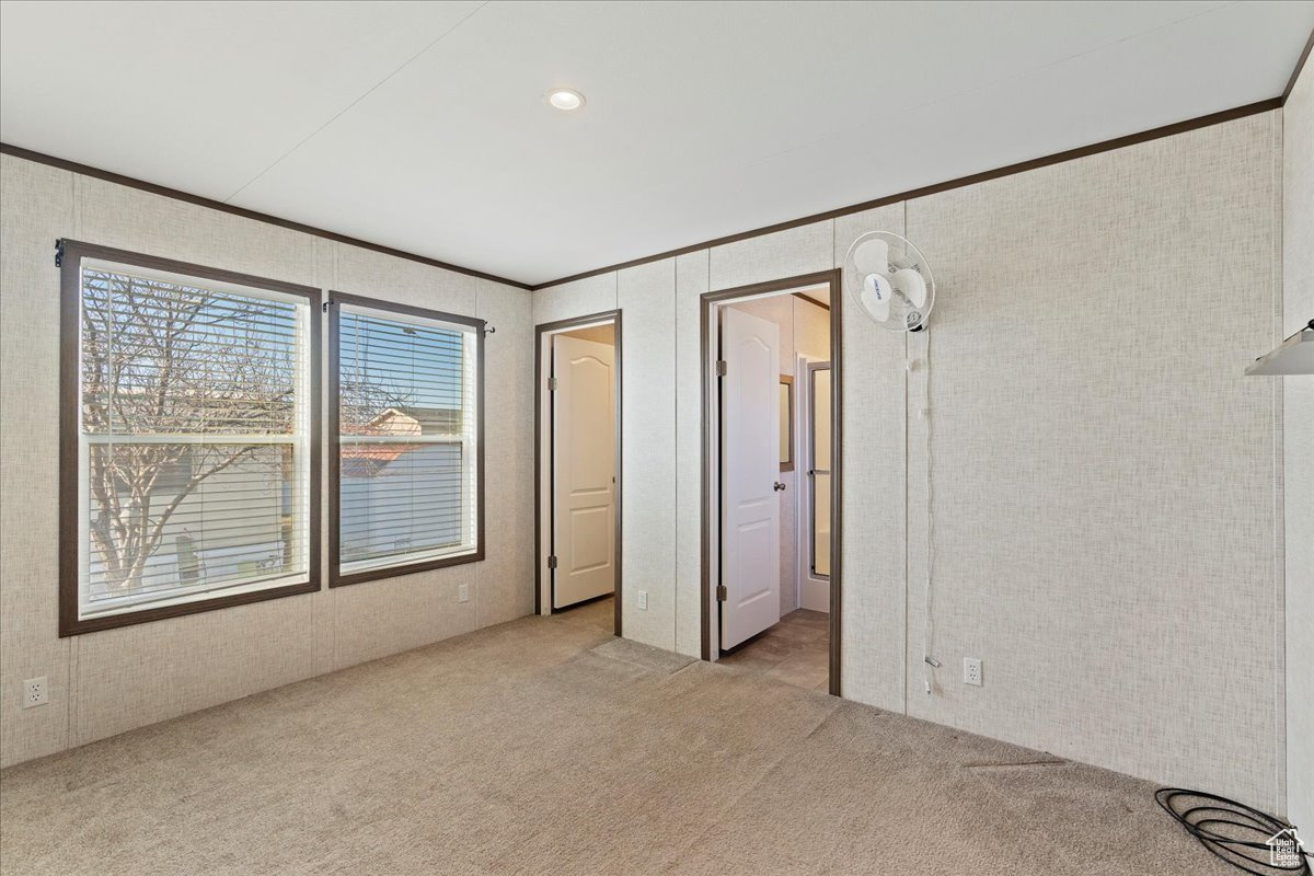 Unfurnished bedroom featuring light carpet and crown molding