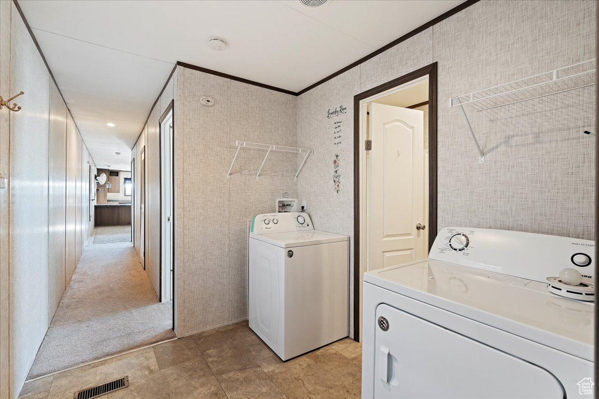 Laundry area with ornamental molding, washing machine and dryer, and light carpet