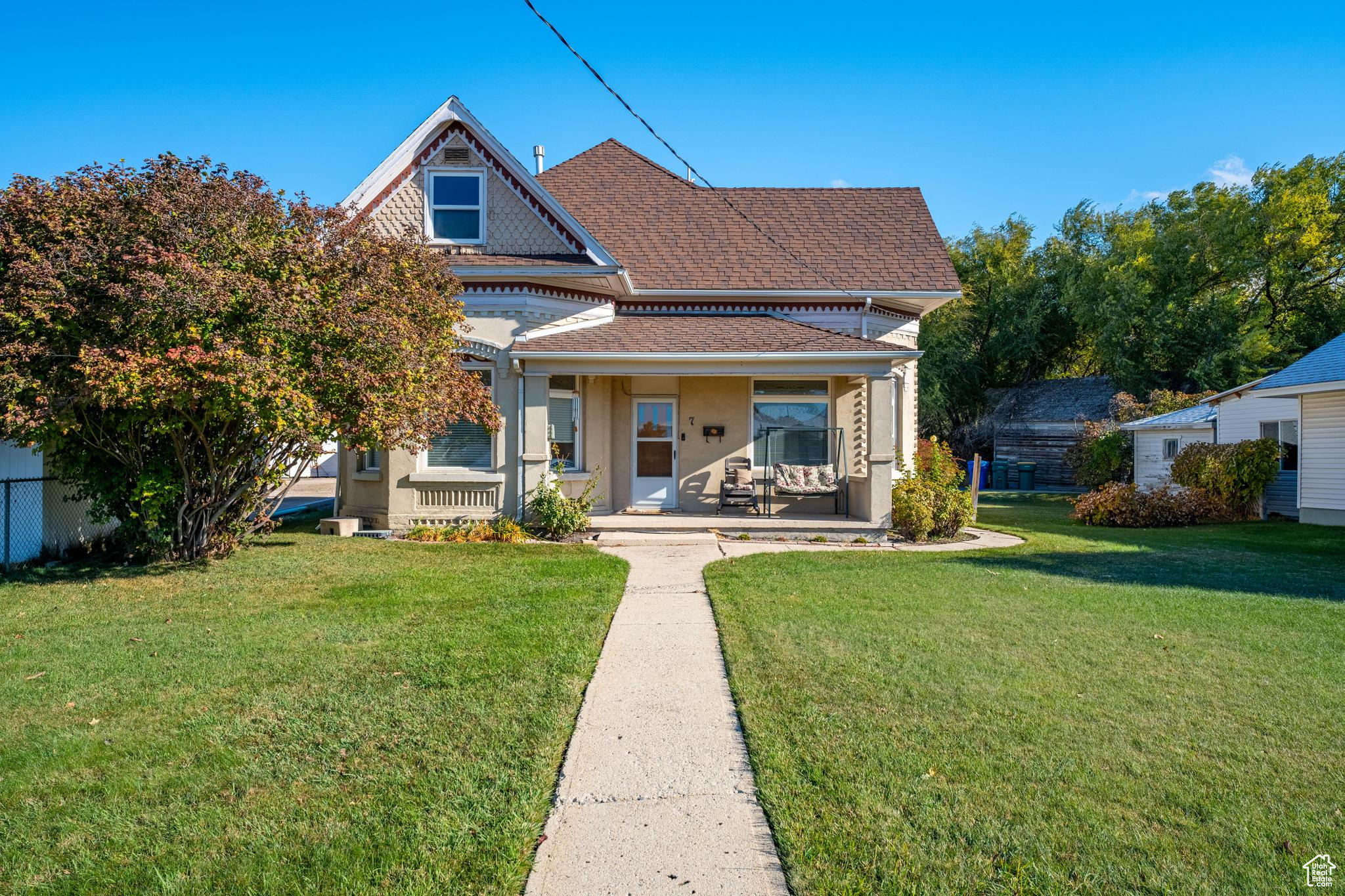 Rear view of house featuring a lawn and a porch