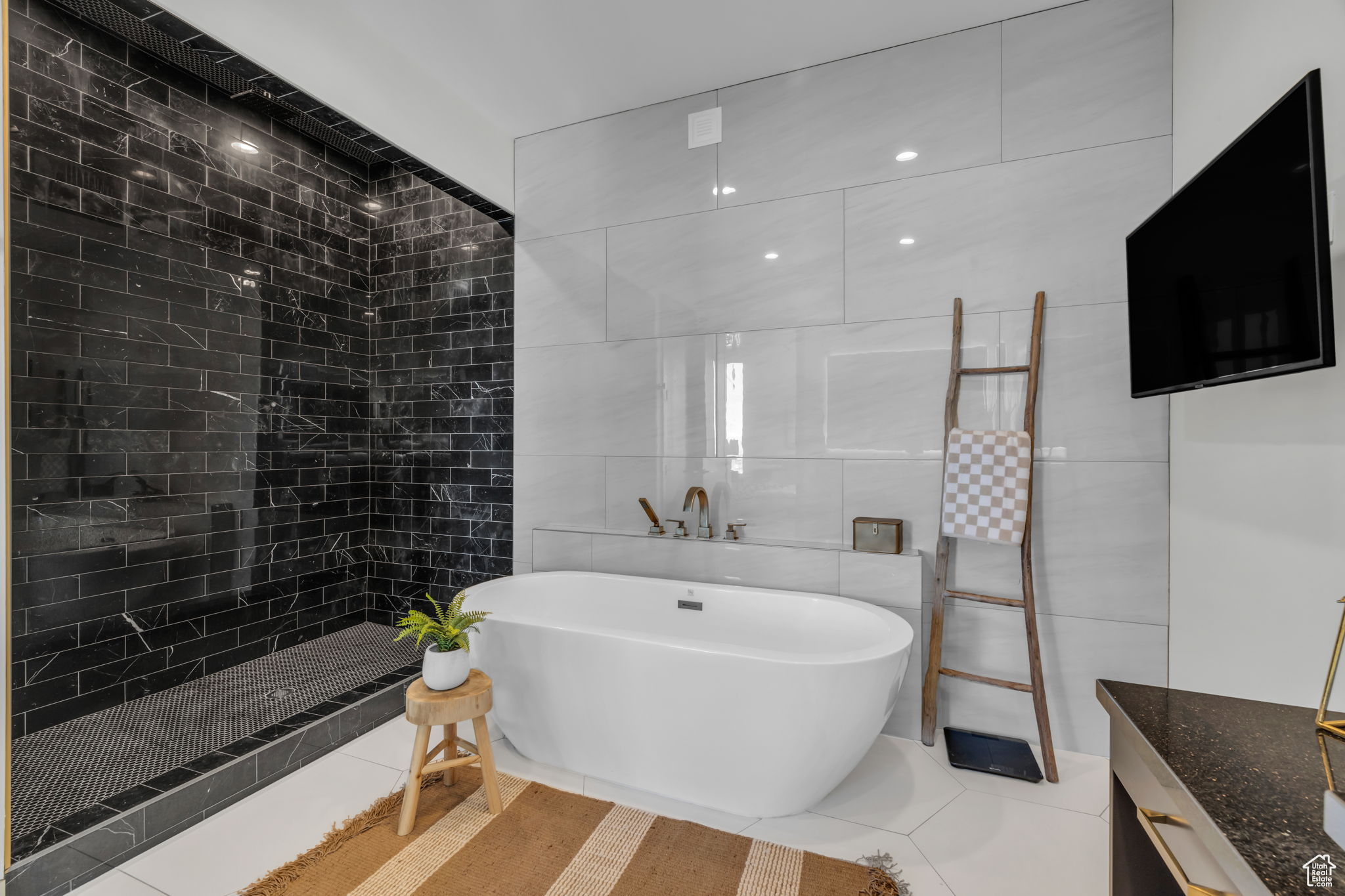 Bathroom with tile patterned floors, tile walls, and shower with separate bathtub