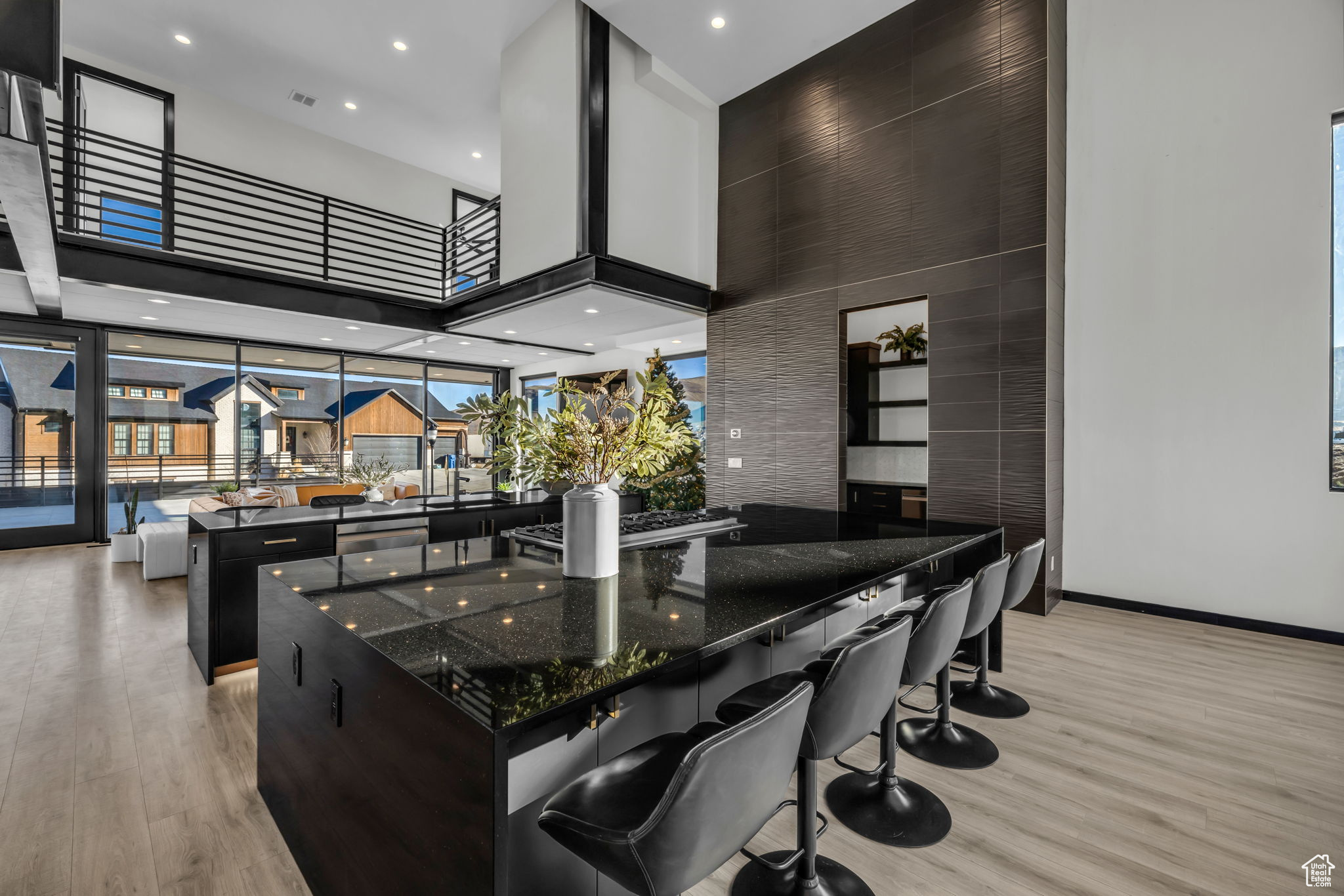 Kitchen featuring a kitchen breakfast bar, dark stone counters, a high ceiling, light hardwood / wood-style floors, and a large island