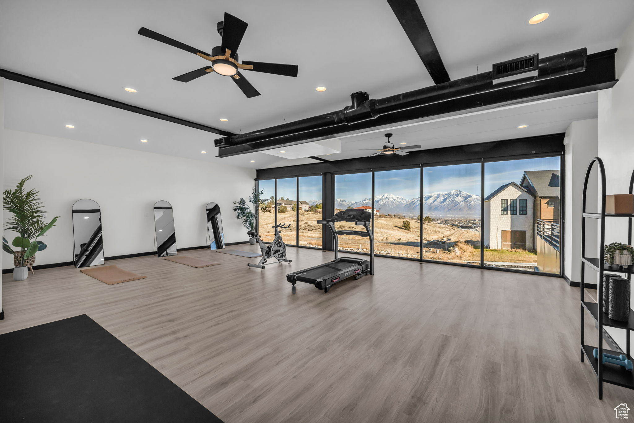 Exercise room with ceiling fan, a mountain view, wood-type flooring, and a wall of windows