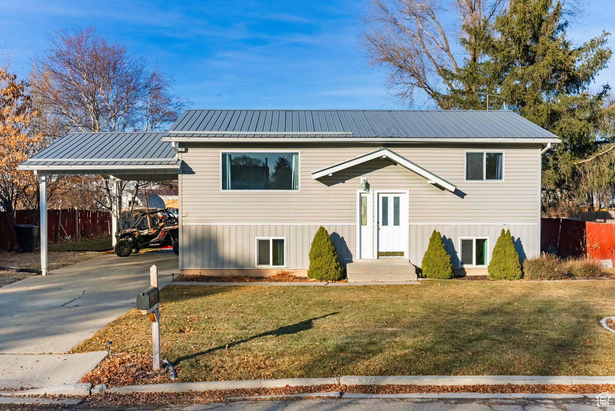 Raised ranch with a front lawn and a carport