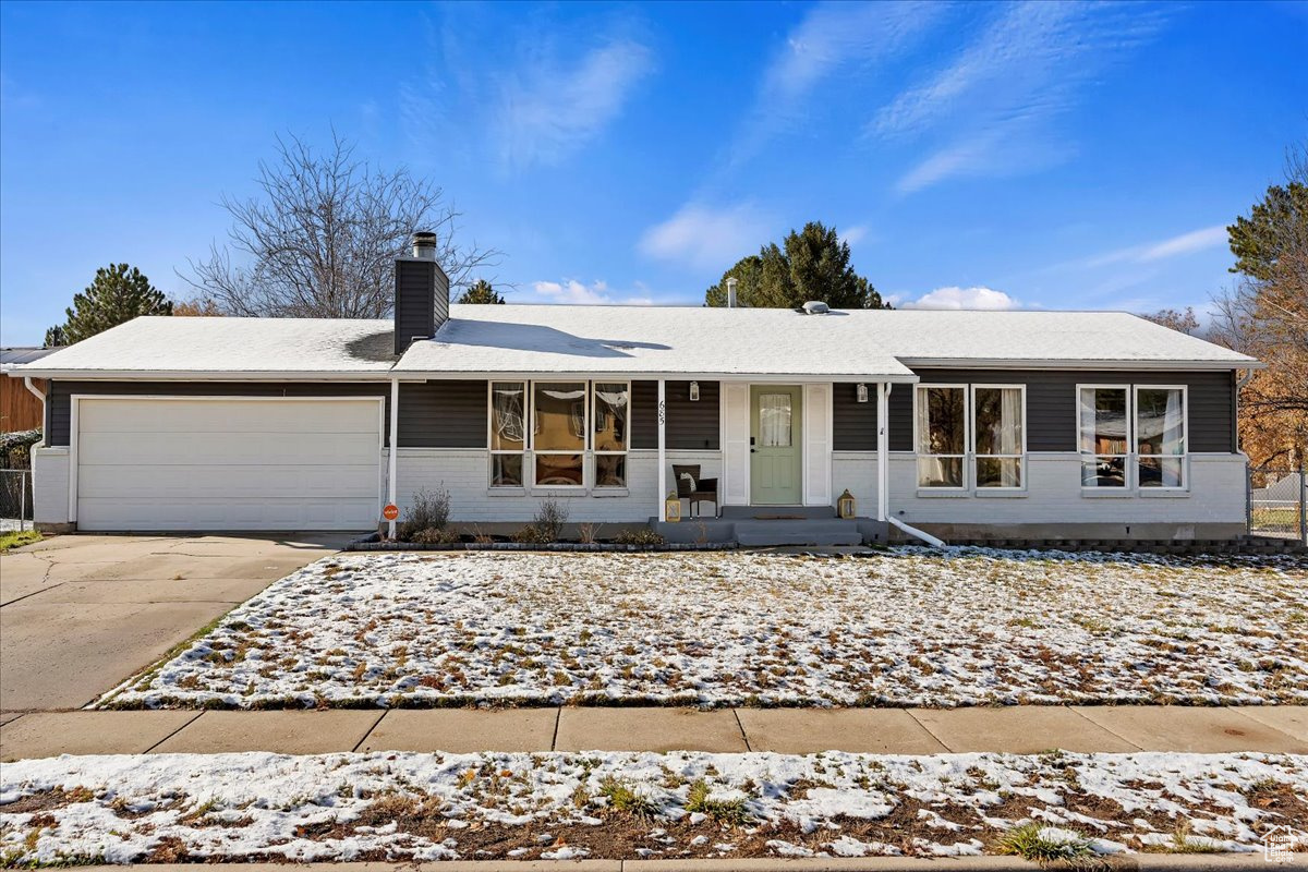 Ranch-style home featuring covered porch and a garage