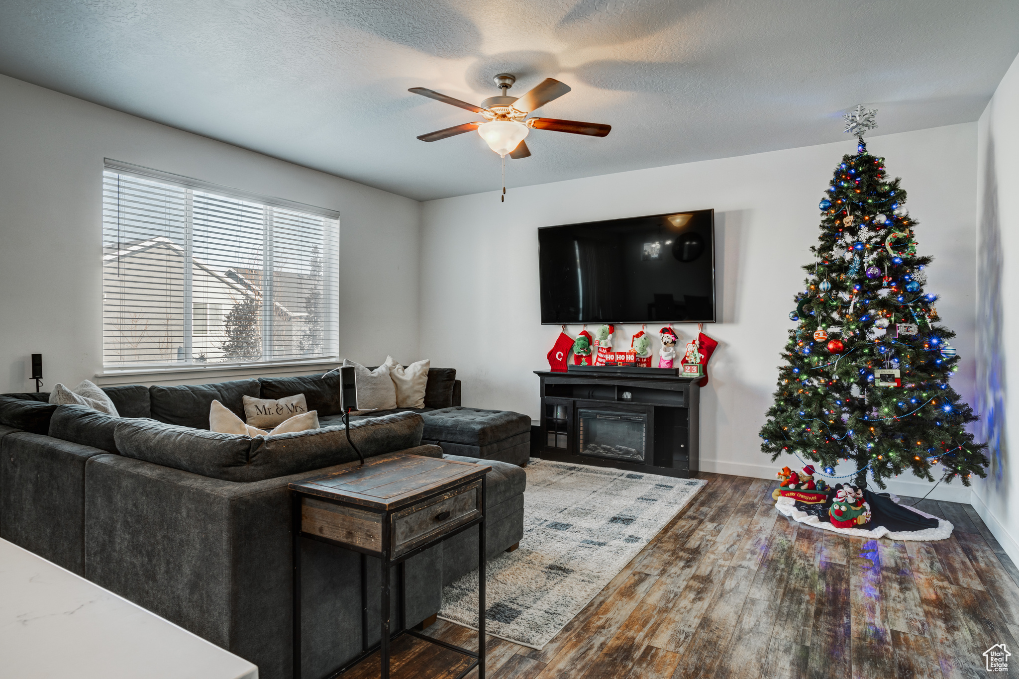 Living room with hardwood / wood-style floors, ceiling fan, and a textured ceiling