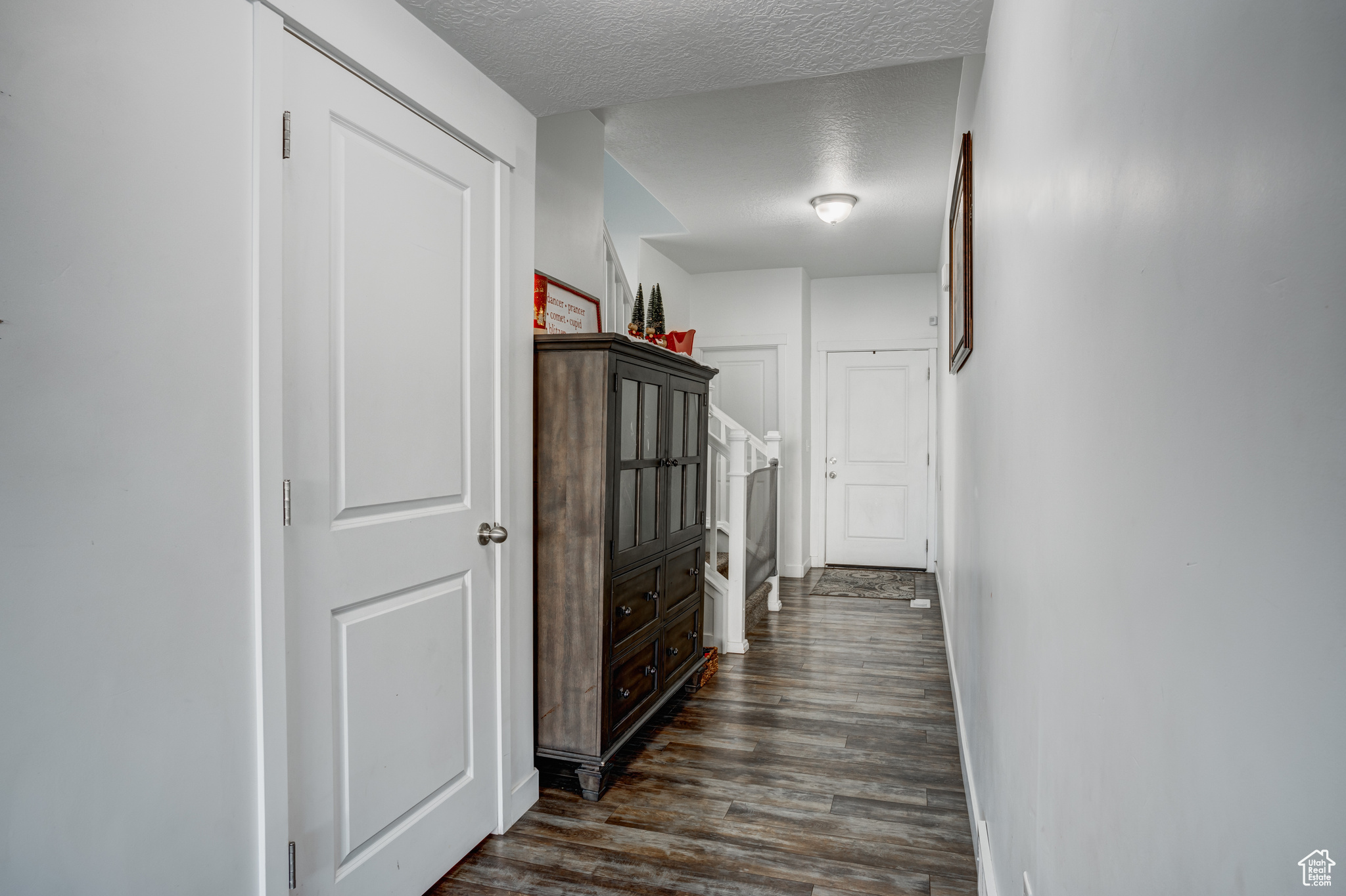 Hall with a textured ceiling and dark hardwood / wood-style floors