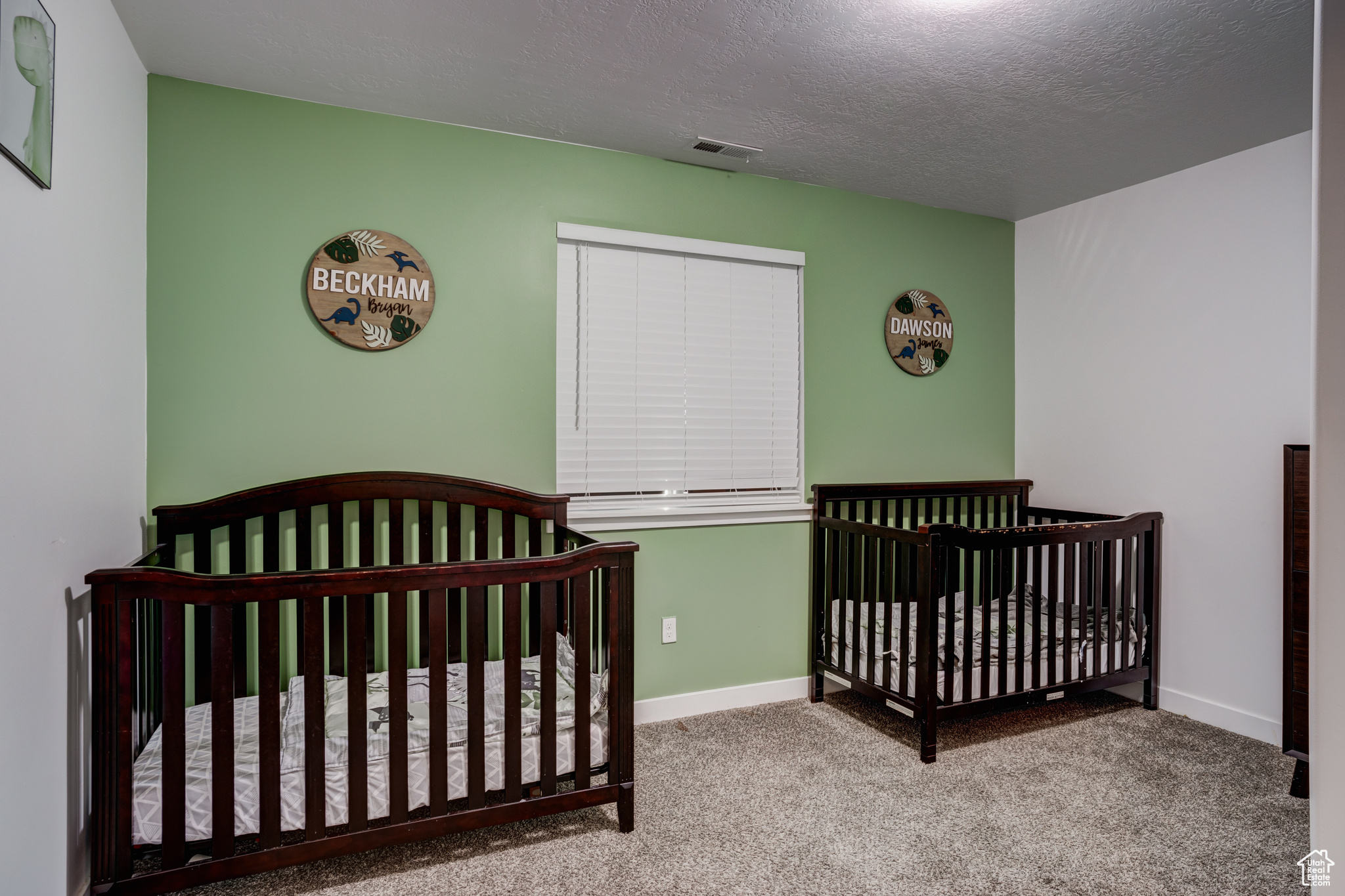 Carpeted bedroom with a textured ceiling and a nursery area