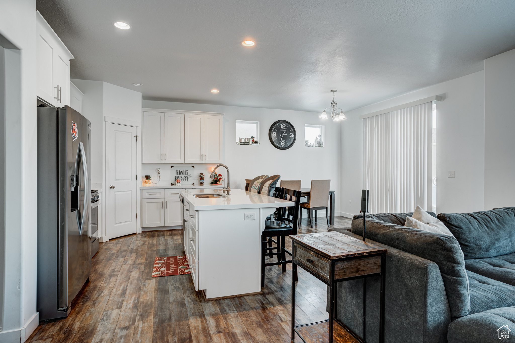 Kitchen with stainless steel refrigerator with ice dispenser, dark hardwood / wood-style flooring, a kitchen island with sink, sink, and white cabinetry