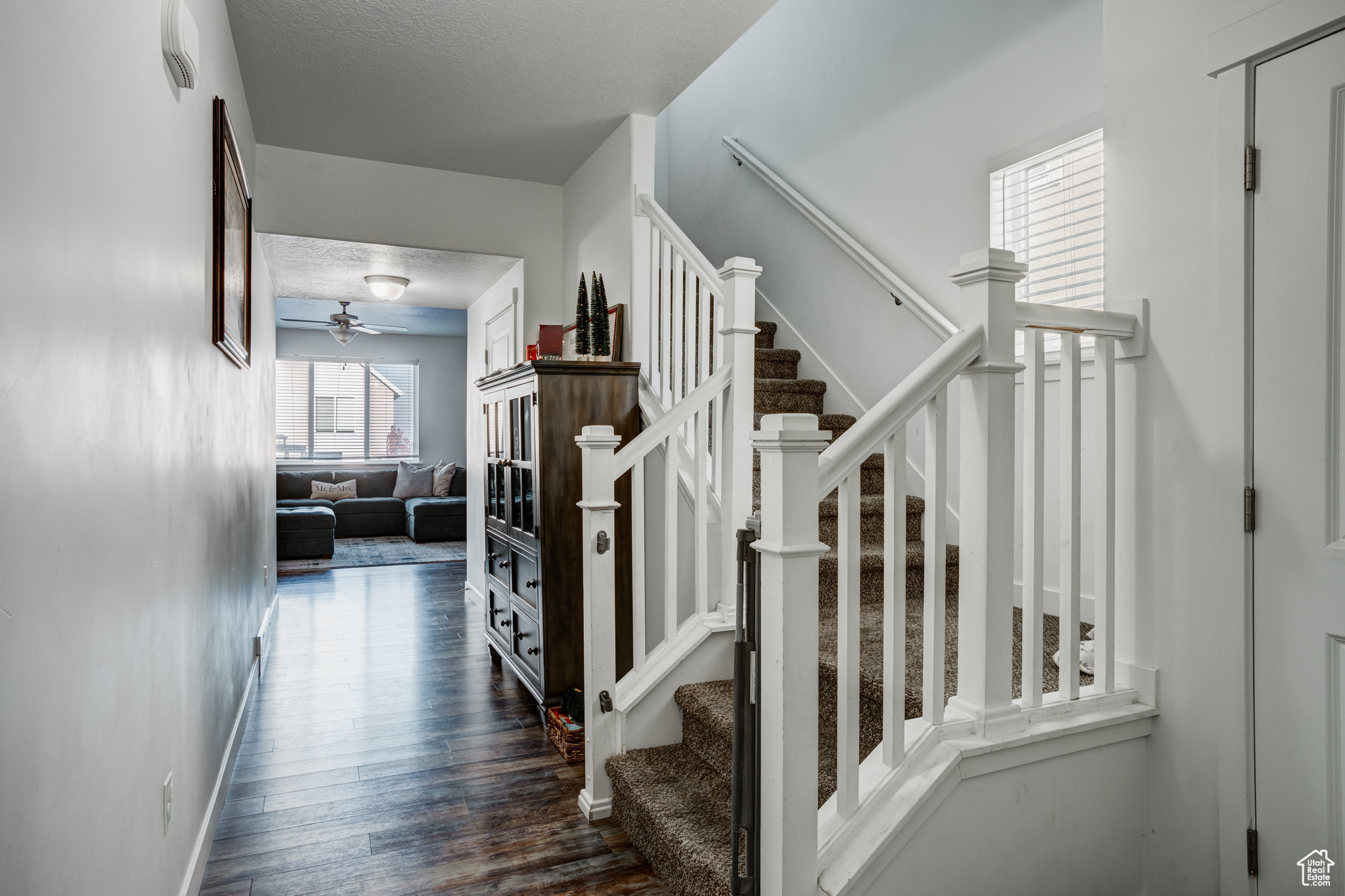 Stairs featuring hardwood / wood-style floors, ceiling fan, and a textured ceiling